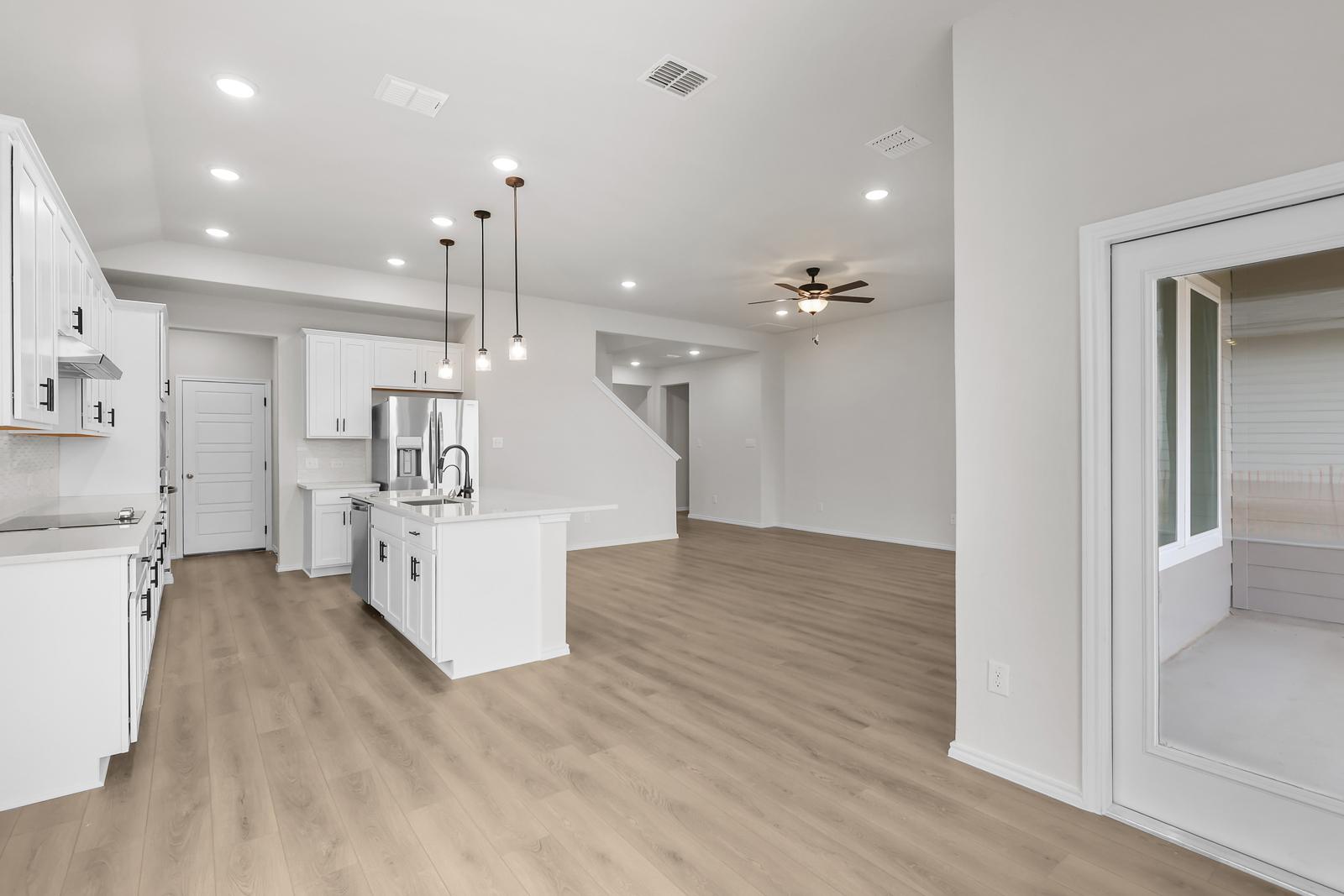 Open-concept kitchen and living area in The Sequoia C featuring white cabinetry, a center island, and wood-style flooring.