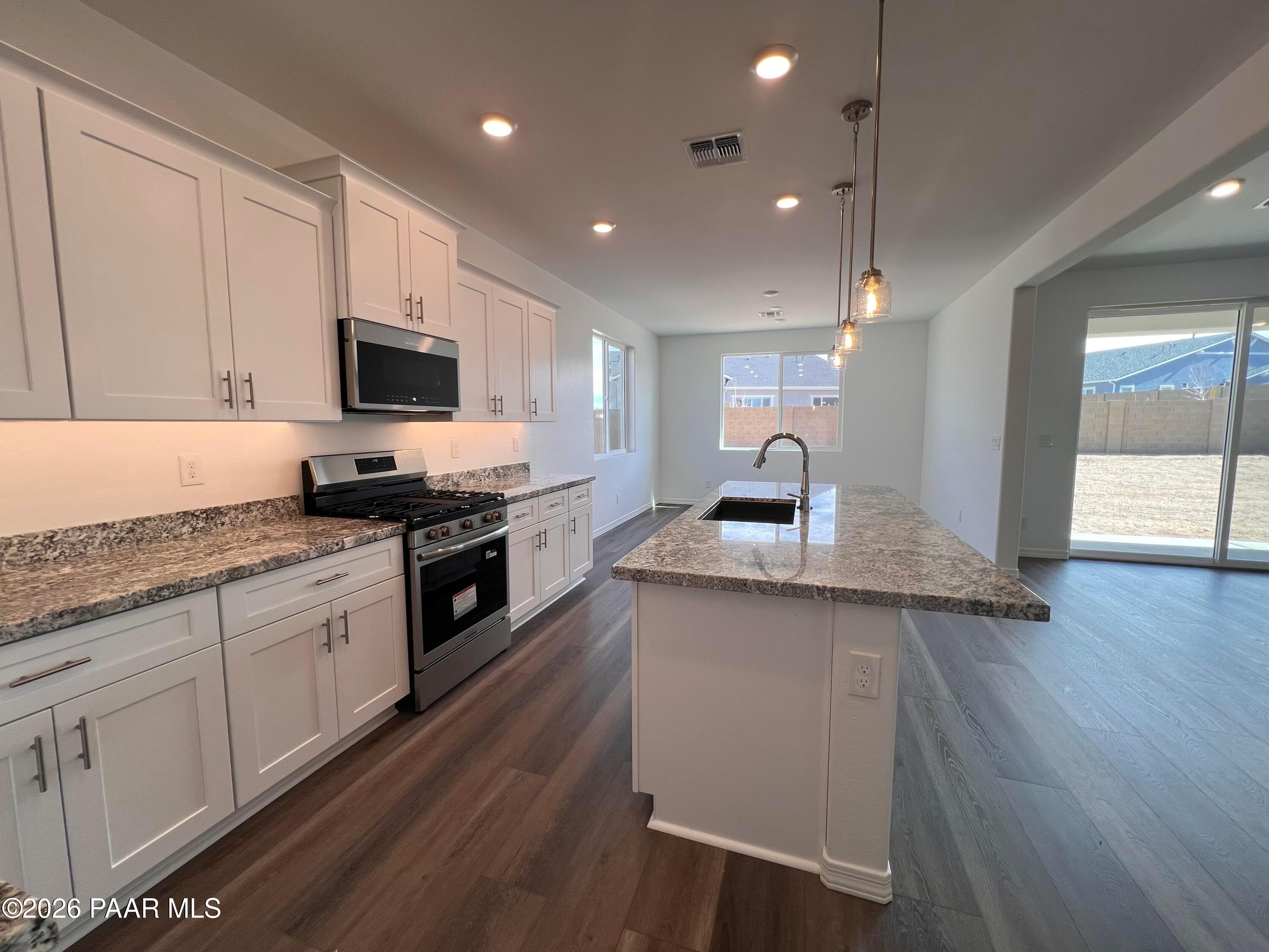 Modern kitchen with white shaker cabinets, granite island sink, stainless appliances in Davidson Homes The Summit A, Prescott AZ