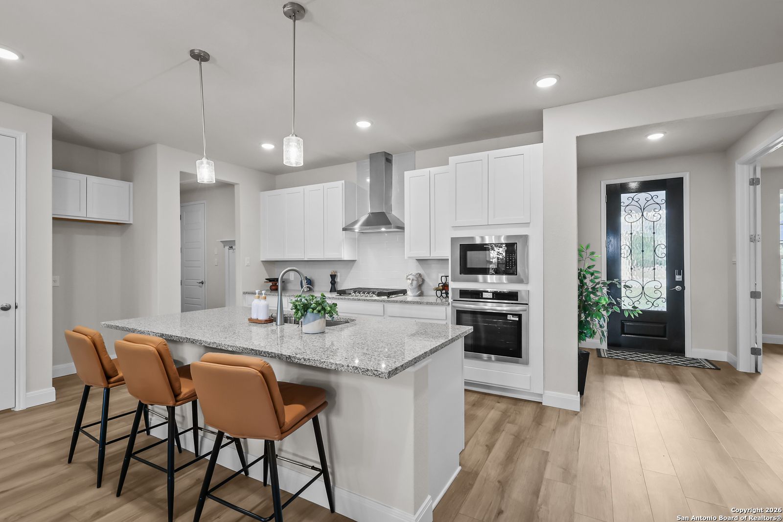 Modern open-concept kitchen with white cabinets, granite island, stainless appliances in The Lanier H by Davidson Homes, Ladera, San Antonio