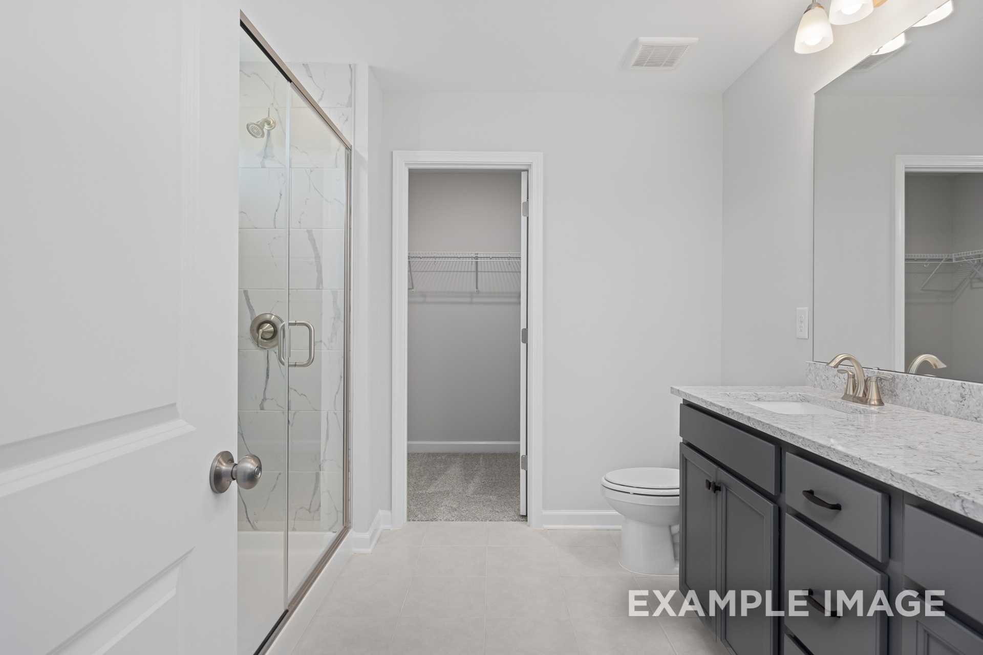 Spacious master bathroom in The Grace C with frameless glass shower, double vanity, quartz counters, and walk-in closet