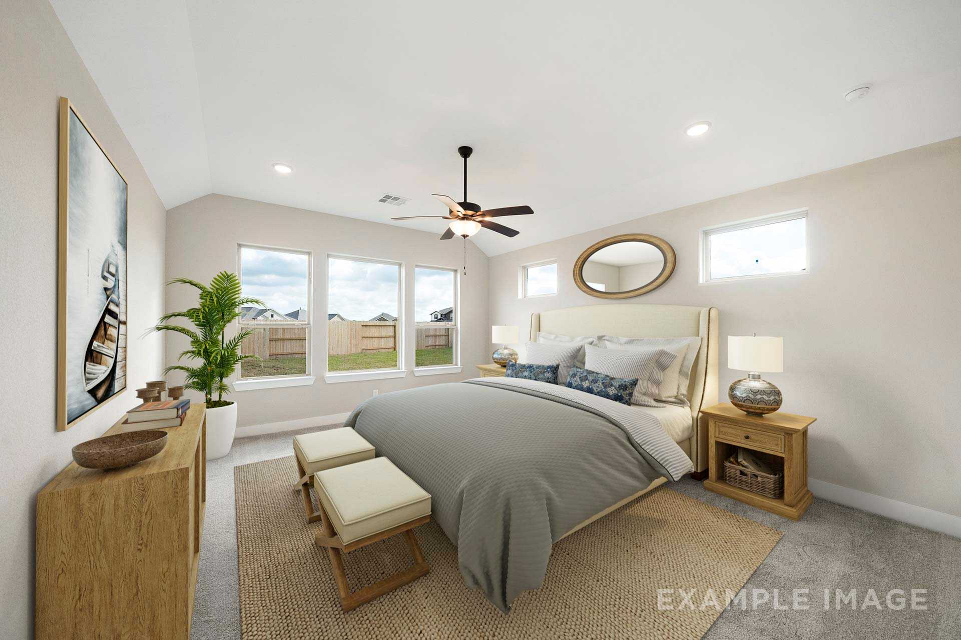 Spacious master suite in The Elizabeth A featuring plush gray king bed, ceiling fan, large windows, and neutral decor