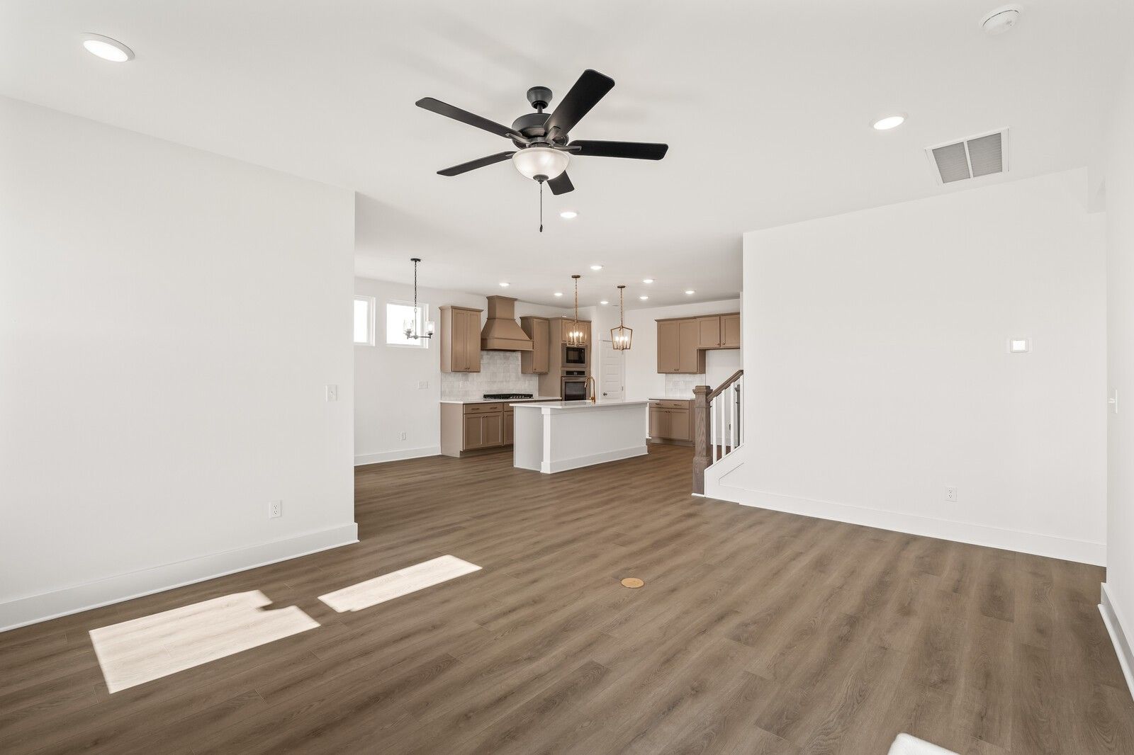 Open-concept kitchen with white island and cabinets, hardwood floors, ceiling fan in Davidson Homes The Ash A, Gallatin, TN