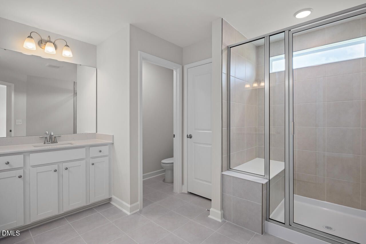 Modern bathroom with walk-in tile shower and white vanity in The Graham floor plan at Springvale, Fuquay-Varina.