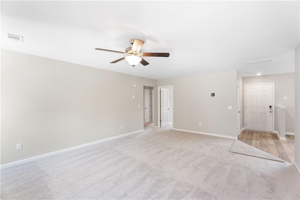 Spacious open living room with beige walls, carpeted floor, ceiling fan in The Washington 3-bedroom home, Phenix City, Alabama