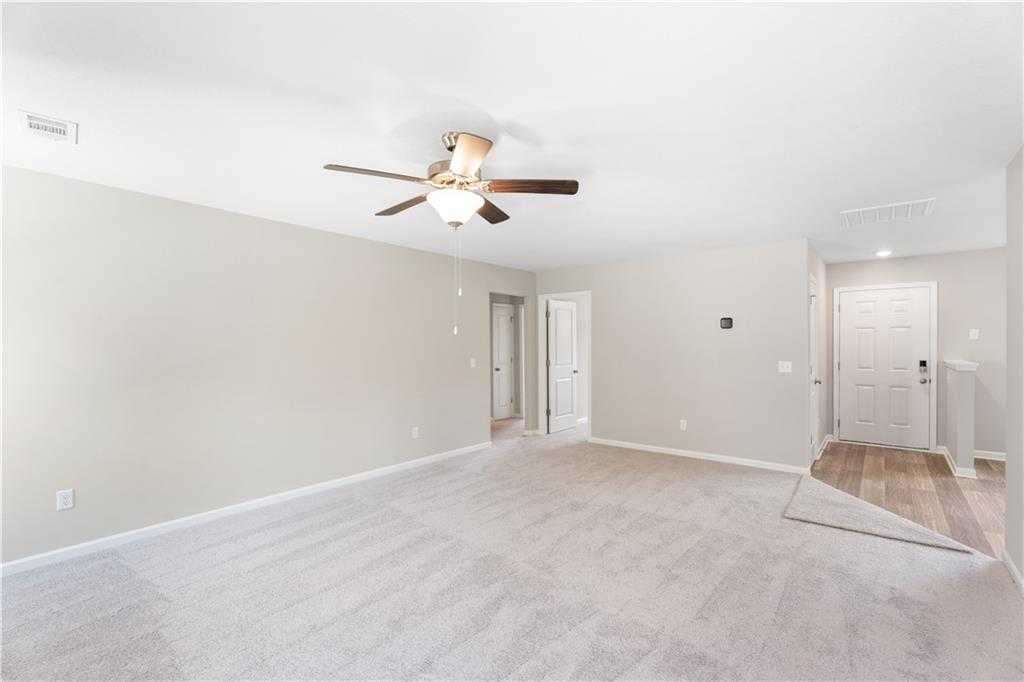 Spacious open living room with beige walls, carpeted floor, ceiling fan in The Washington 3-bedroom home, Phenix City, Alabama