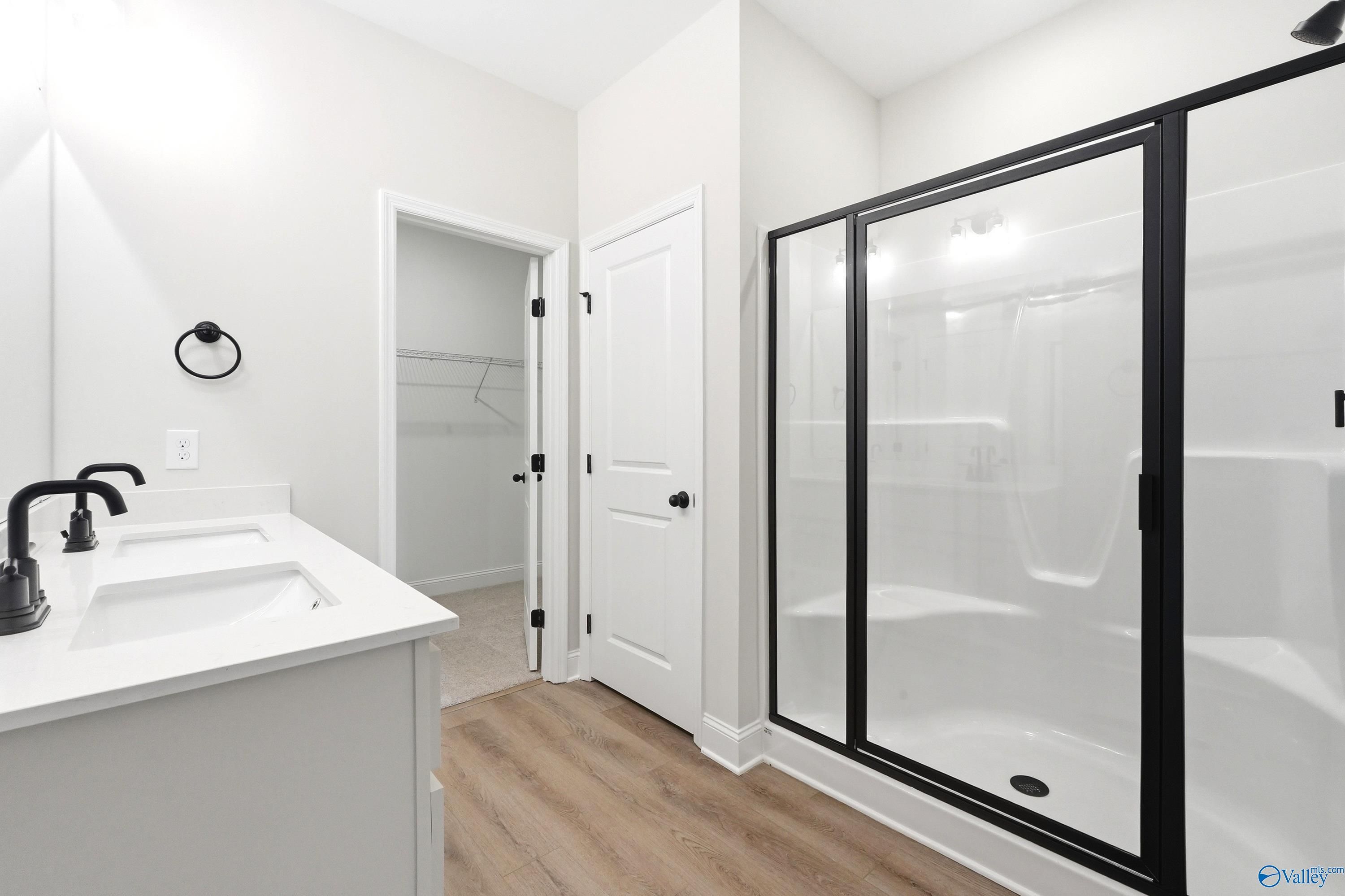 Modern primary bathroom with double vanity, walk-in shower, and closet in The Franklin floor plan at Ricketts Farm, Athens.