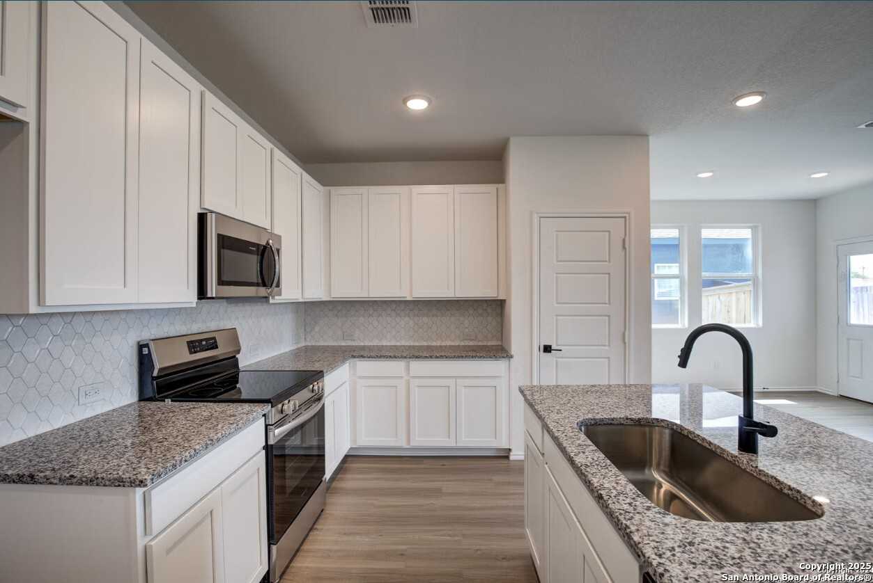 Modern white kitchen with granite countertops, stainless steel appliances, subway tile backsplash in Davidson Homes The Daphne H, Seguin, TX
