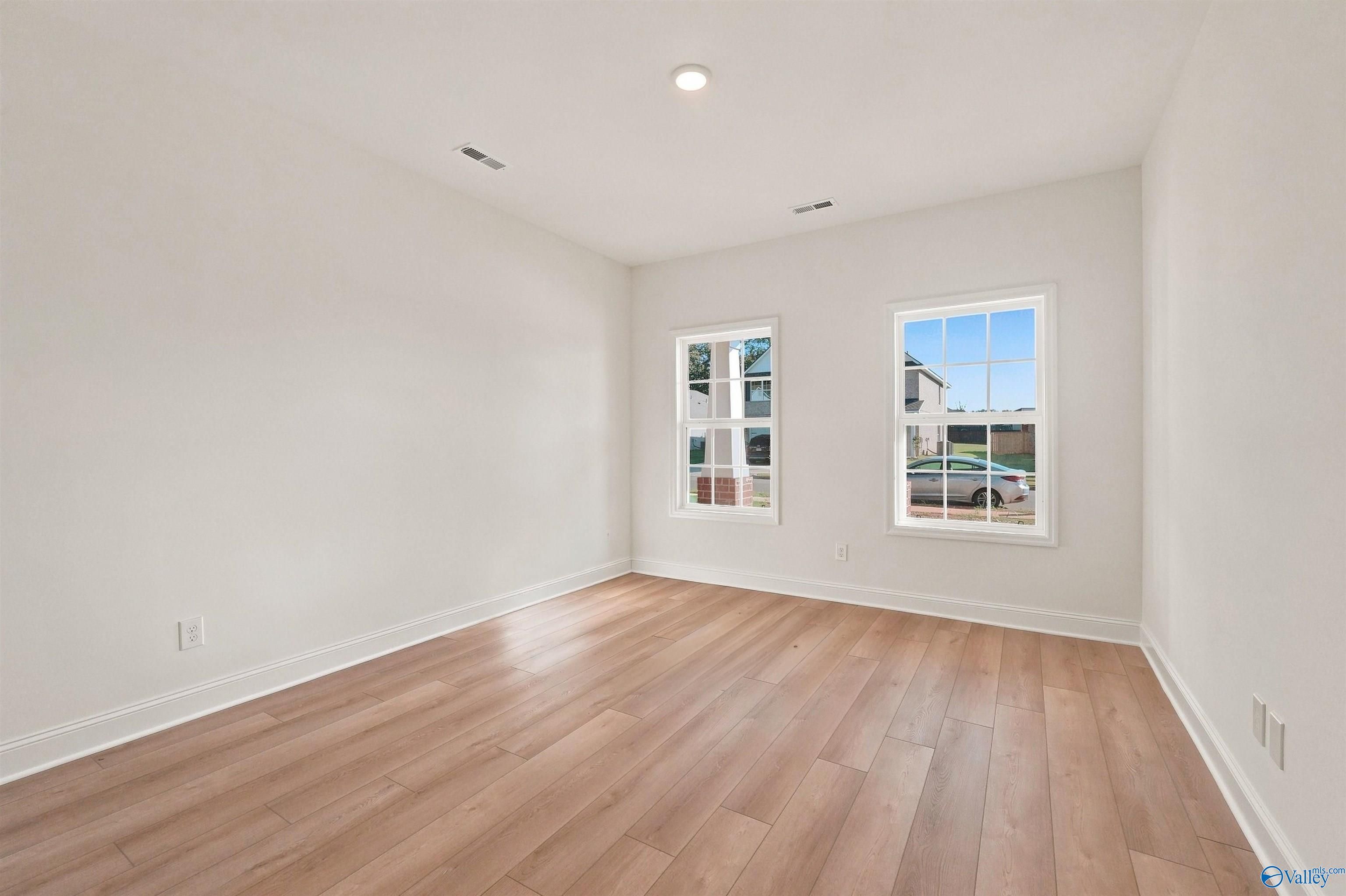 Bright bedroom with wood-look flooring and white walls in The Chelsea C floor plan at Creek Grove in New Market, Alabama.