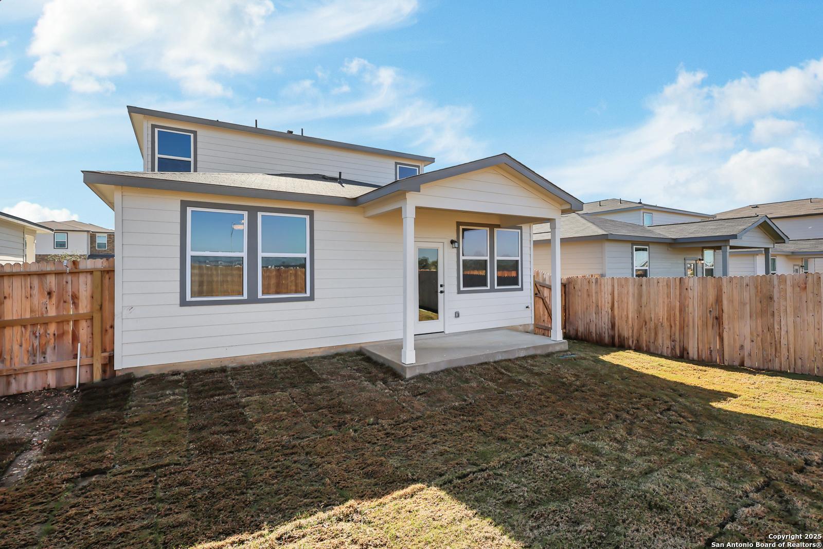 Two-story beige home with covered patio, large windows, and fenced backyard in Applewhite Meadows, San Antonio, Texas
