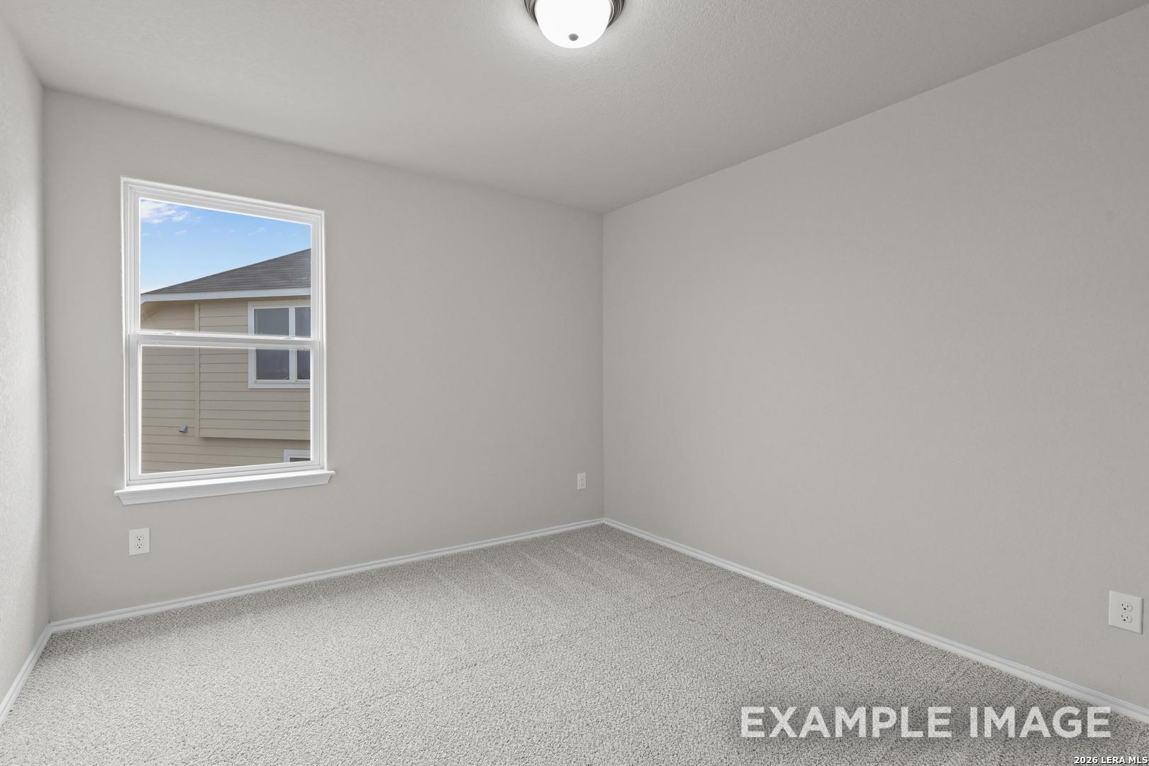Bright empty bedroom with neutral walls, carpet flooring, and window at Davidson Homes' The Murray H in Horizon Pointe, Converse, Texas.