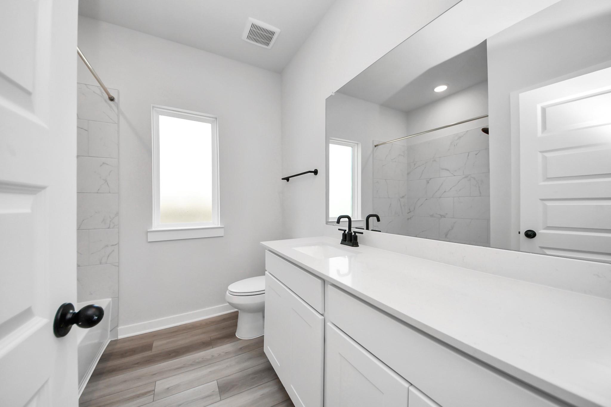 Modern bathroom with white vanity, marble-tiled shower, and matte black fixtures in The Everett C home at River Ranch Meadows.