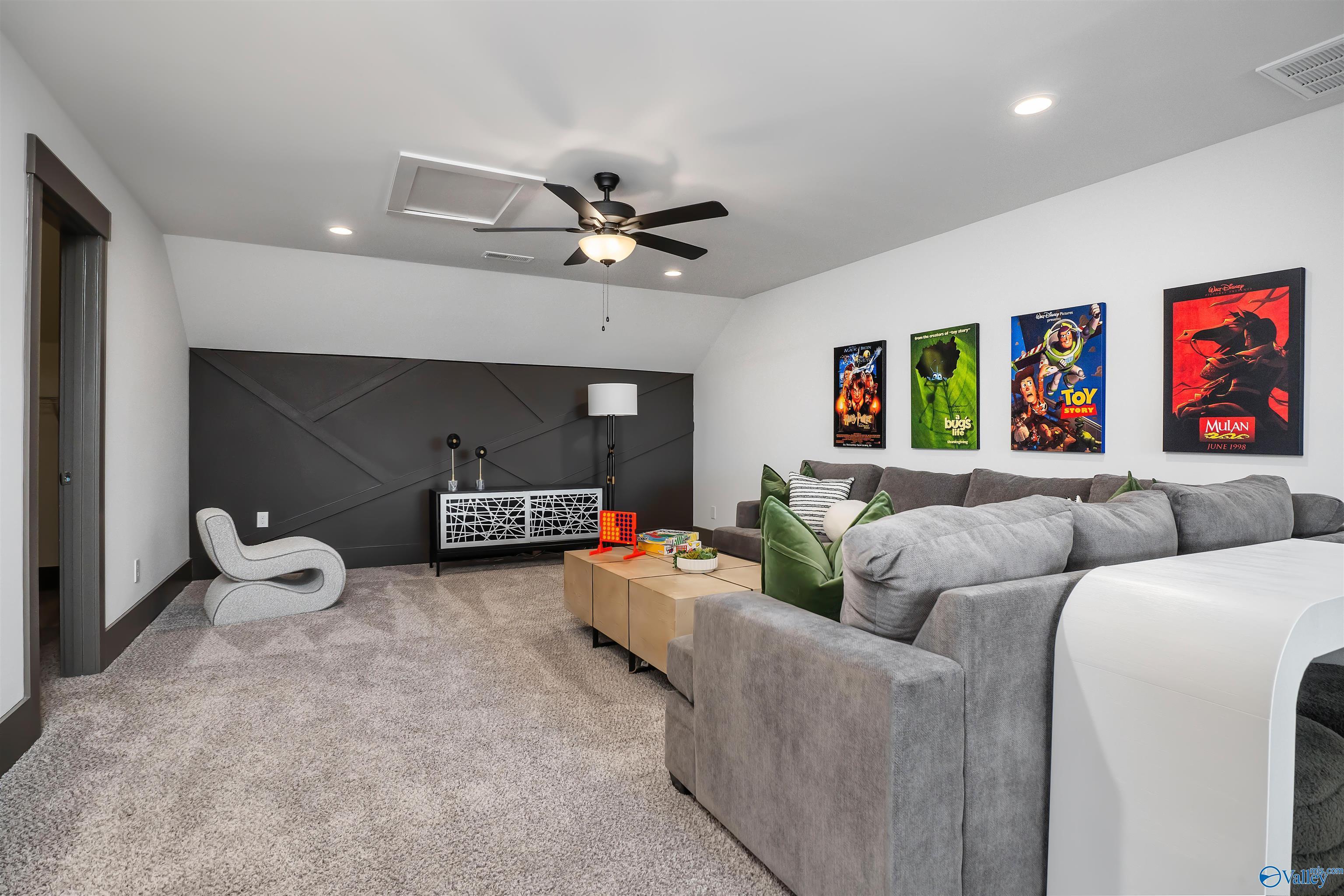 Cozy bonus media room with gray sectional sofa, movie posters, and shiplap accent wall in Davidson Homes The Rockford B, Madison, Alabama