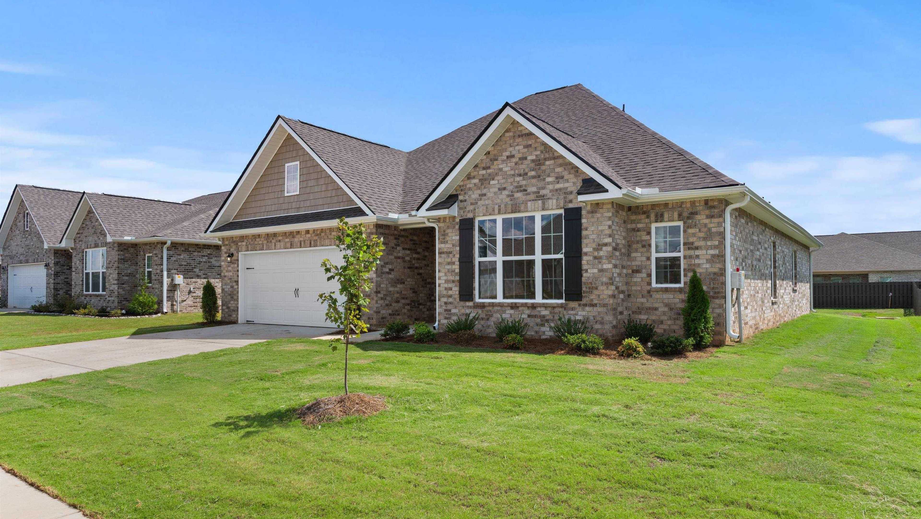 Brick ranch home at Davidson Homes open house, 230 White Horse Way, with garage, shutters, manicured lawn, young tree, blue sky