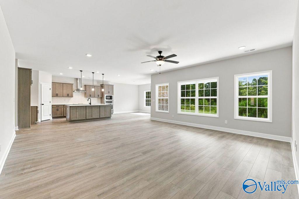 Open-concept great room with luxury vinyl plank flooring, ceiling fan, and large windows in Davidson Homes Rockford plan, Hartselle AL