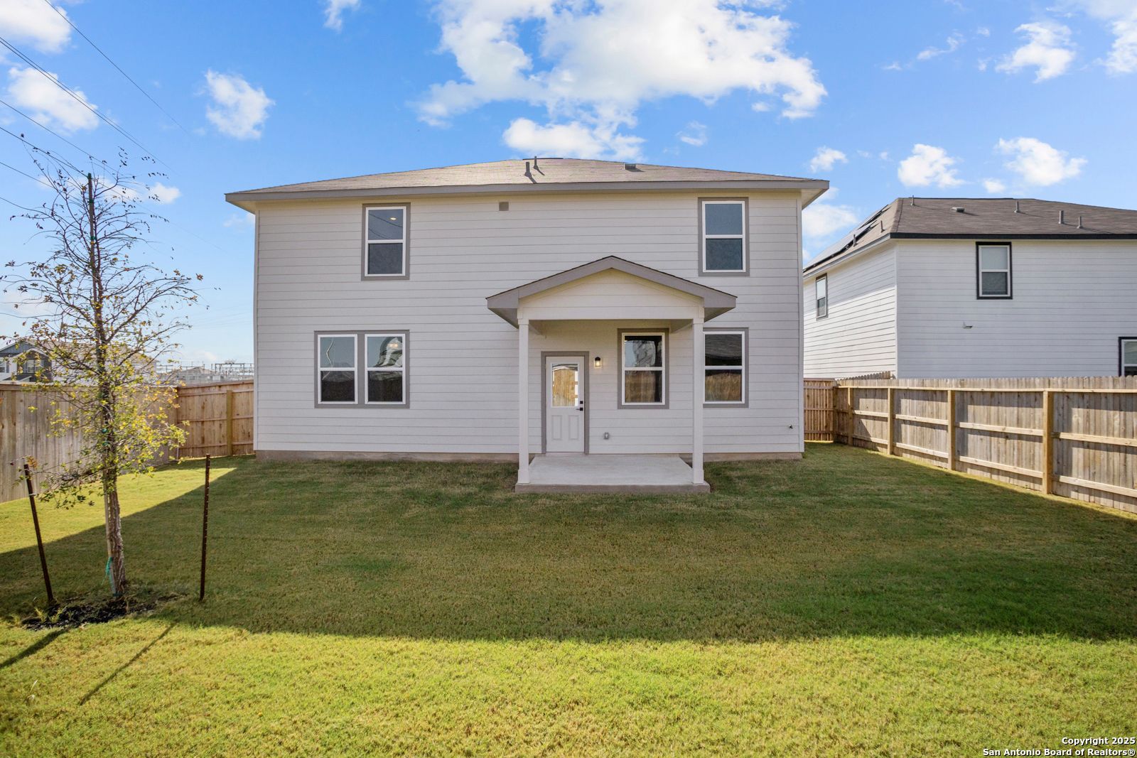 Two-story white Davidson Homes Douglas C with covered back patio and fenced grassy yard in Hannah Heights, Seguin, Texas