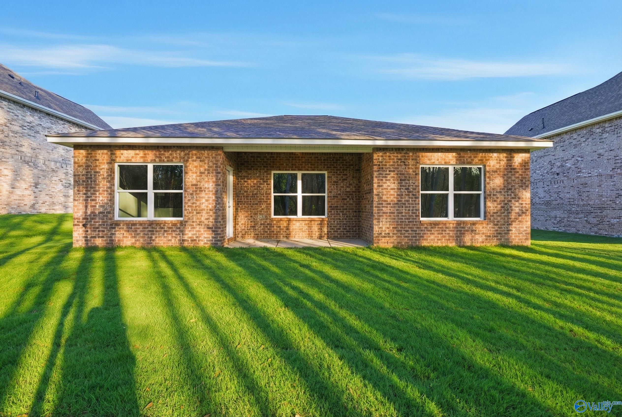 Brick one-story ranch home with gable roof and front windows on lush green lawn in The Highlands, Arab, Alabama