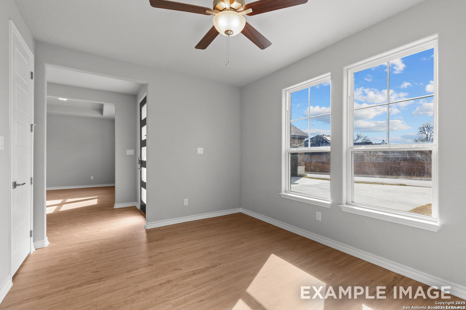 Bright bedroom with wood-look flooring and ceiling fan in The Oxford F floor plan at Potranco Oaks, Castroville, Texas.