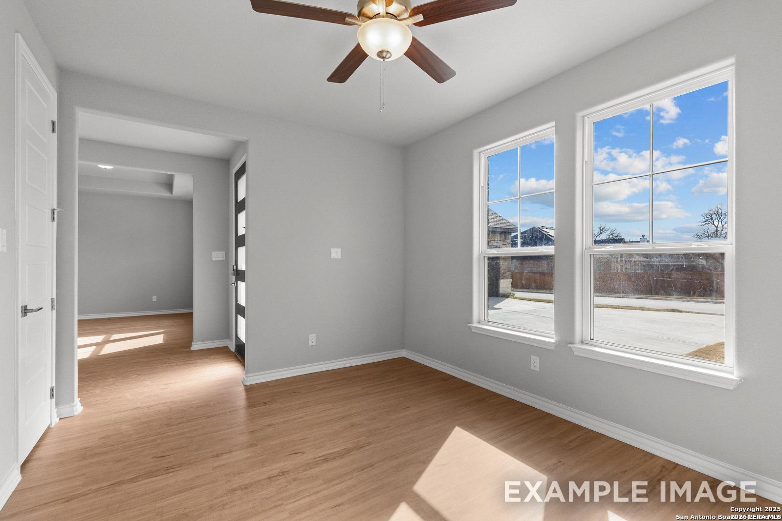 Bright bedroom with wood-look flooring and ceiling fan in The Oxford F floor plan at Potranco Oaks, Castroville, Texas.