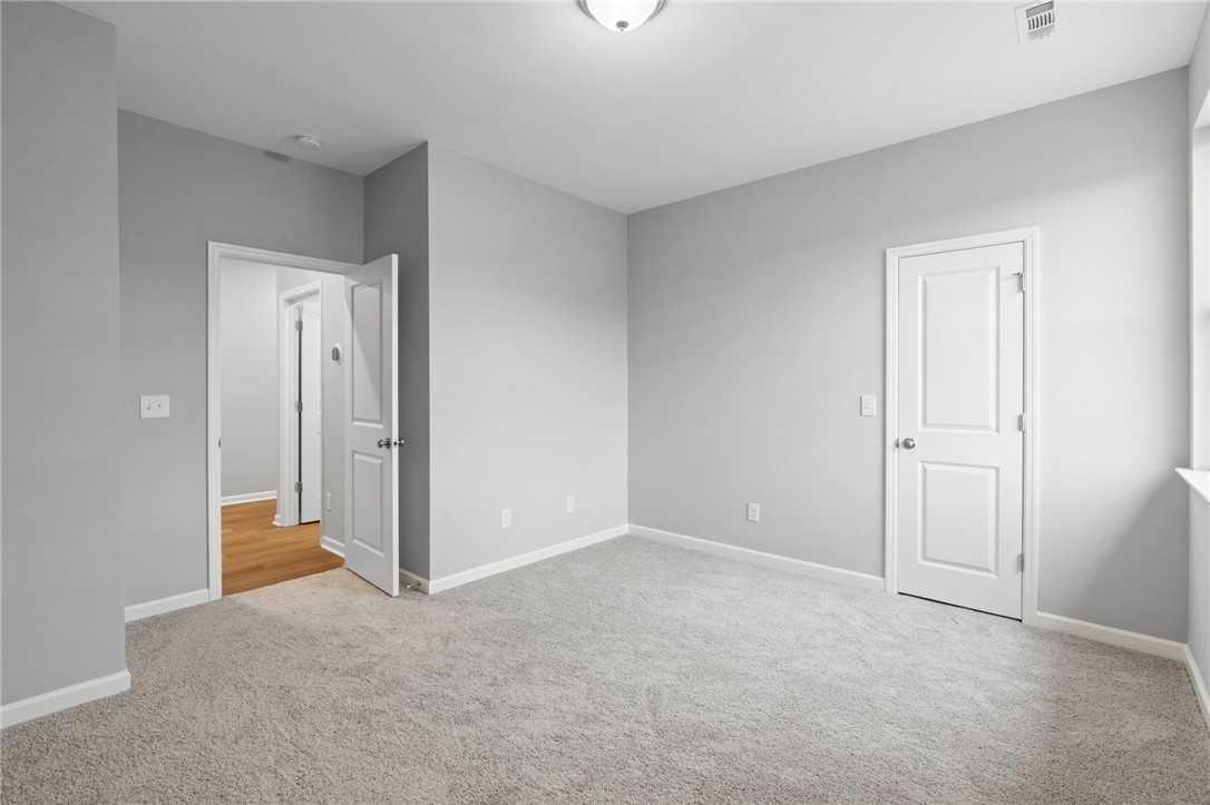Spacious secondary bedroom with gray walls, beige carpet, and adjoining bath in Davidson Homes The Luna B, Opelika, Alabama