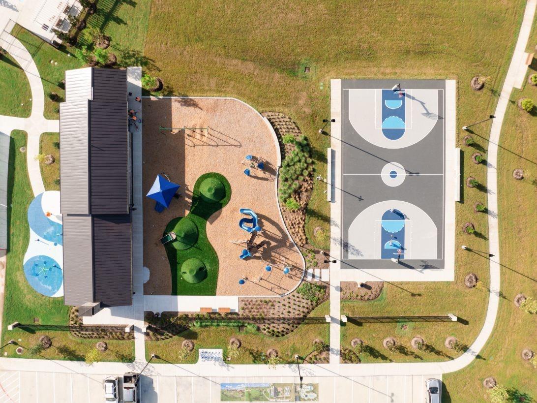 Aerial view of colorful playground with slides, swings, basketball court, and pavilion in Sierra Vista, Rosharon, Texas