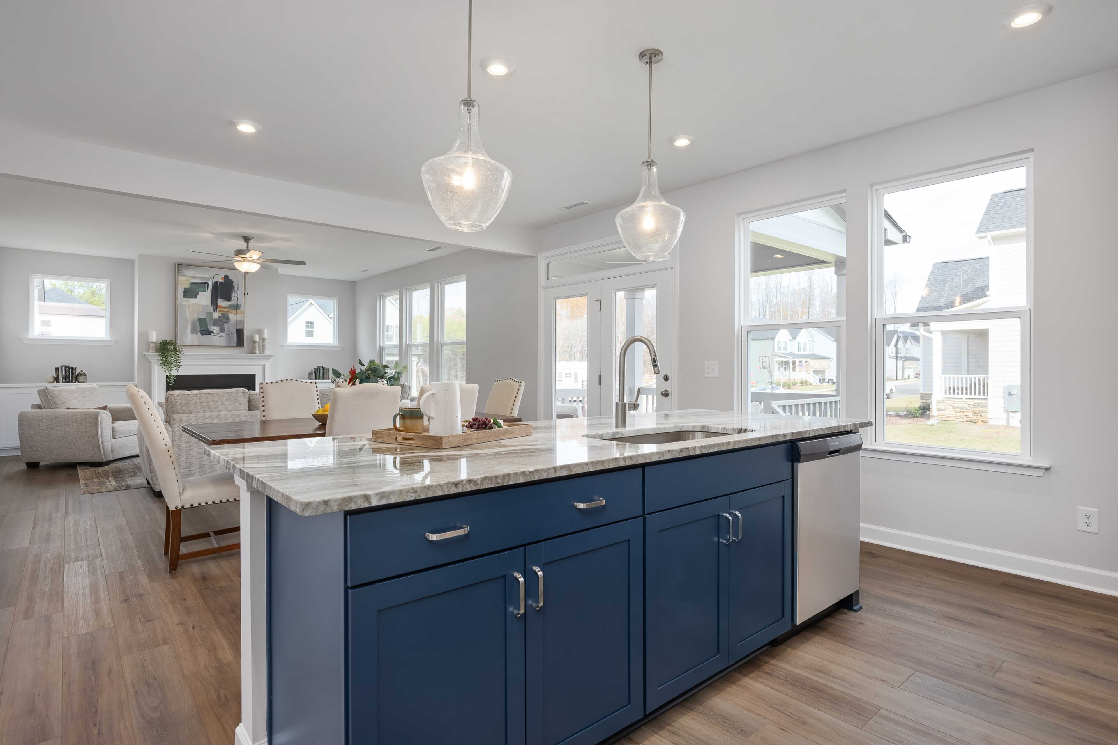 Open-concept kitchen with navy island, granite counters, pendant lights, and hardwood floors at Enclave at Belmont in Belmont NC
