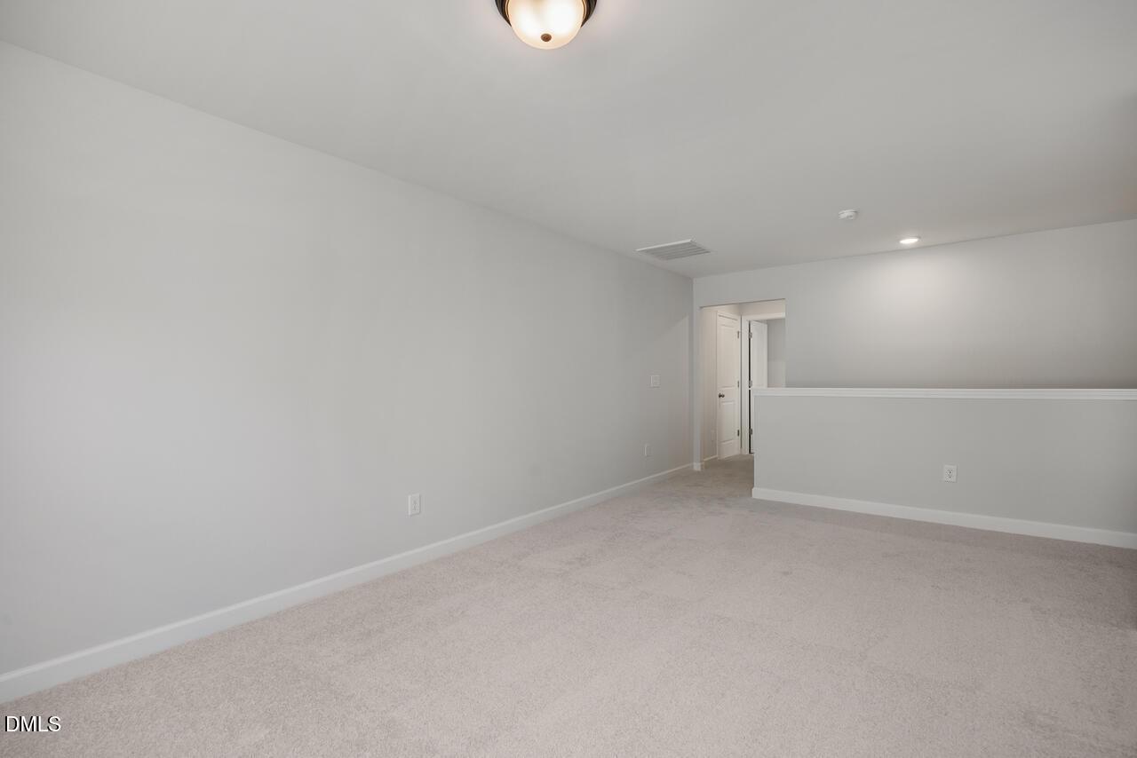 Spacious carpeted loft area in The Birch II E floor plan at Sage on North Main in Wake Forest, North Carolina.