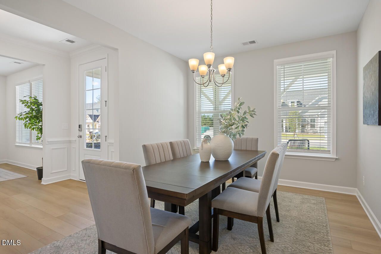 Bright formal dining room with chandelier, dark wood table, and upholstered chairs in Davidson Homes Magnolia A plan, Wendell, NC