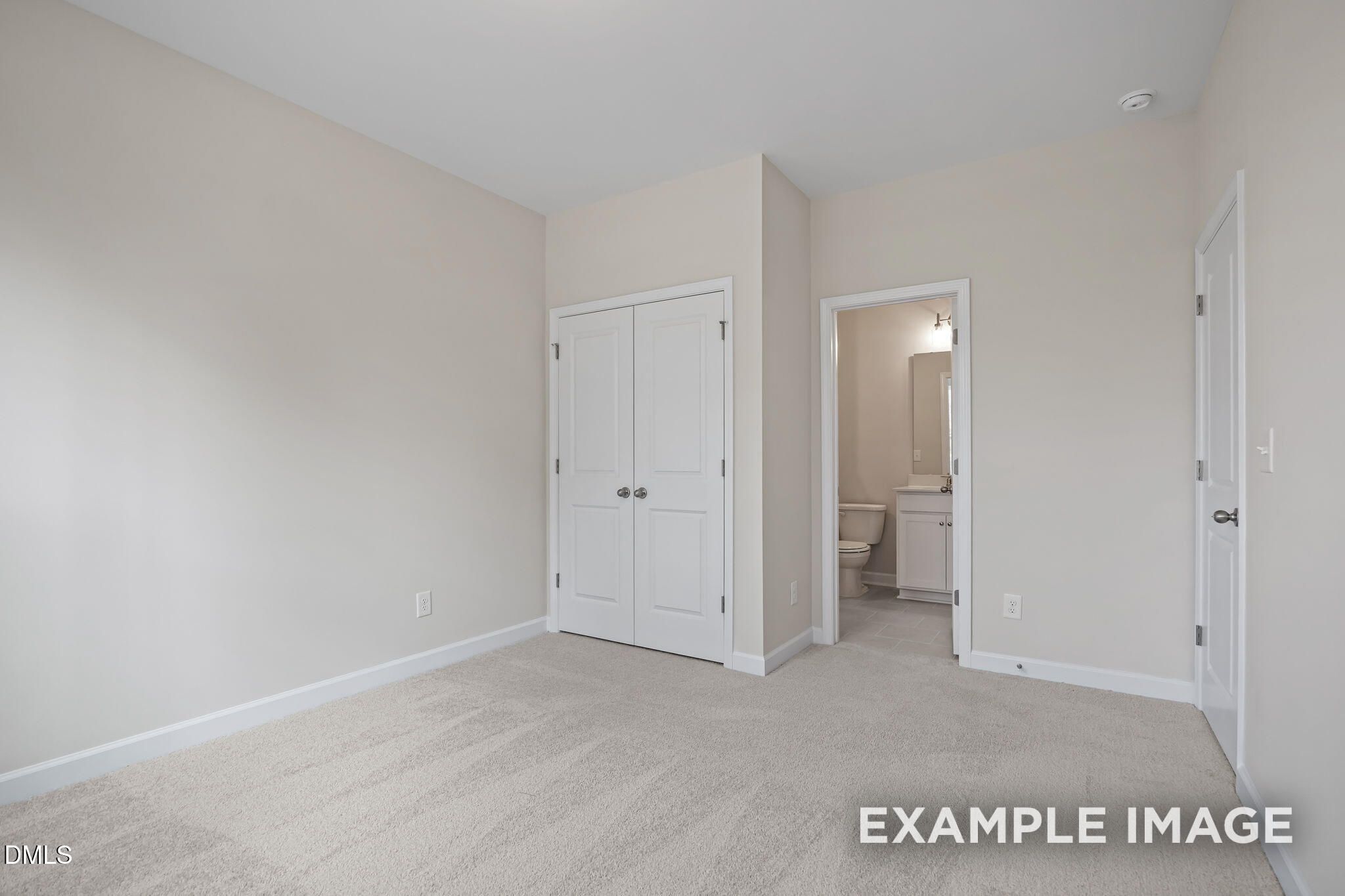 Spacious bedroom with beige walls, plush carpet flooring, double closet doors, and adjacent bathroom in Davidson Homes The Avery, Knightdale, NC