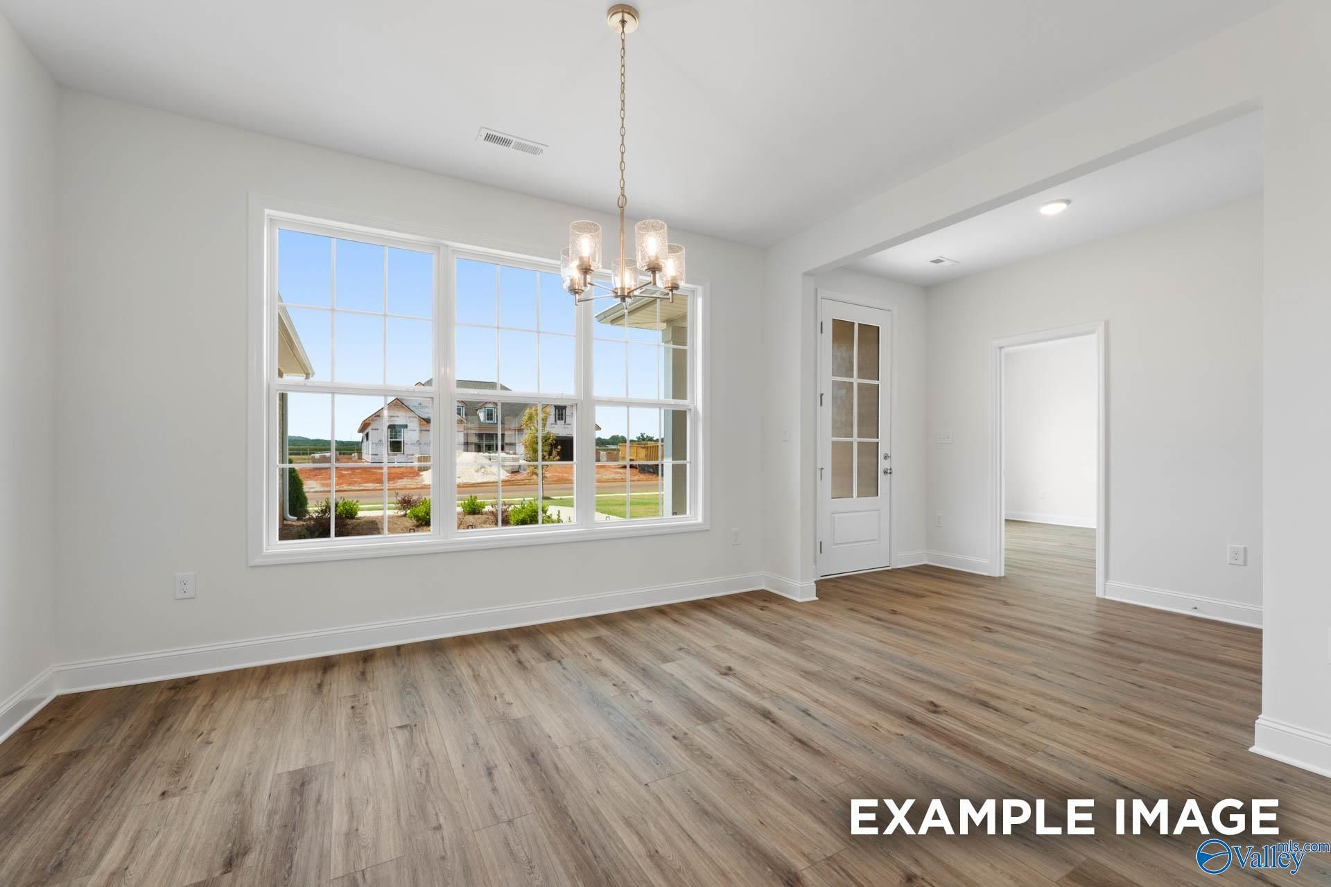 Bright dining room with chandelier, hardwood floors, and large window view in Davidson Homes The Oxford, Riverton Preserve, Huntsville, Alabama