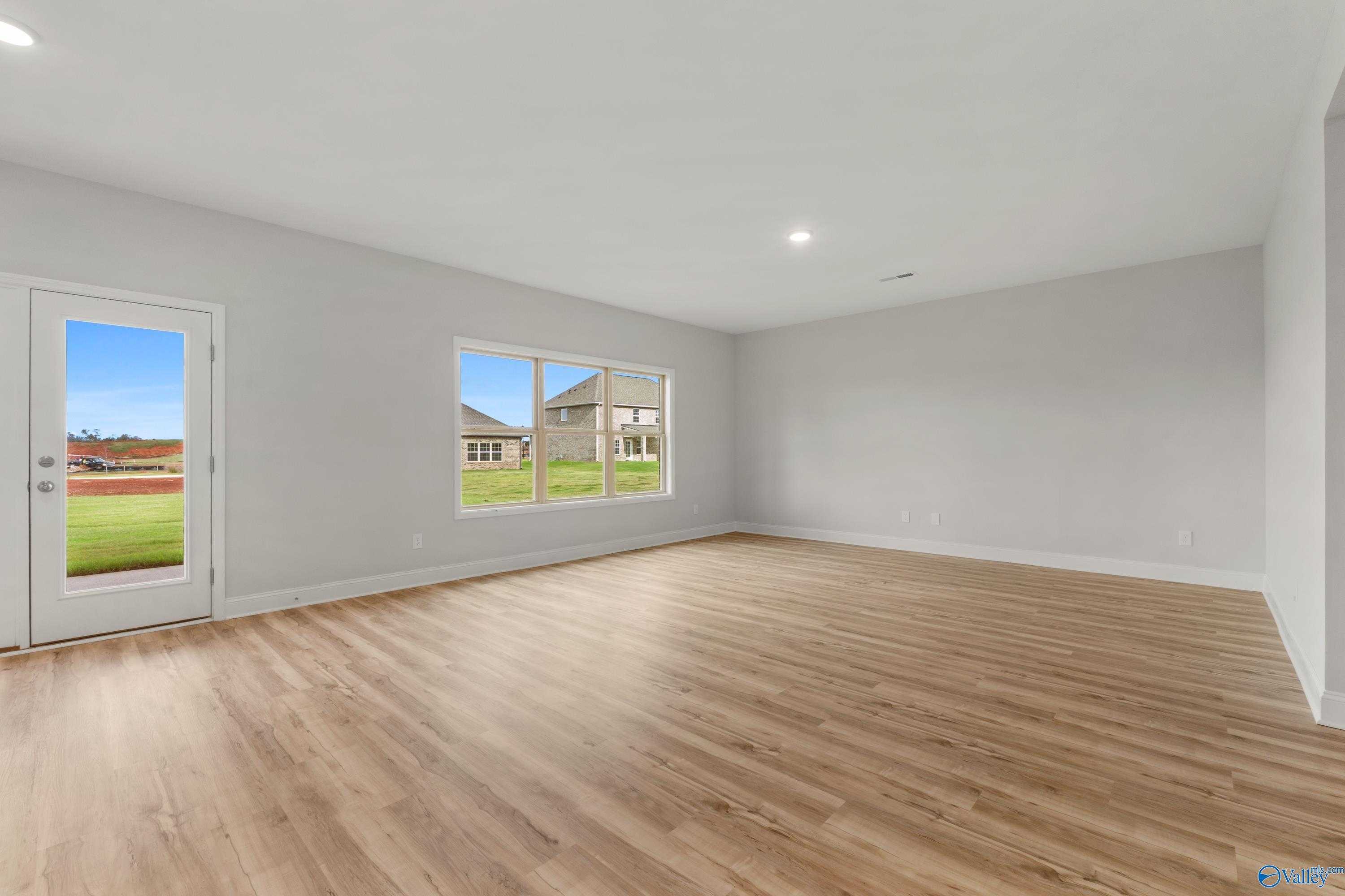 Empty living room with hardwood floors, gray walls, French doors to grassy yard in Davidson Homes Chelsea C, Harvest AL