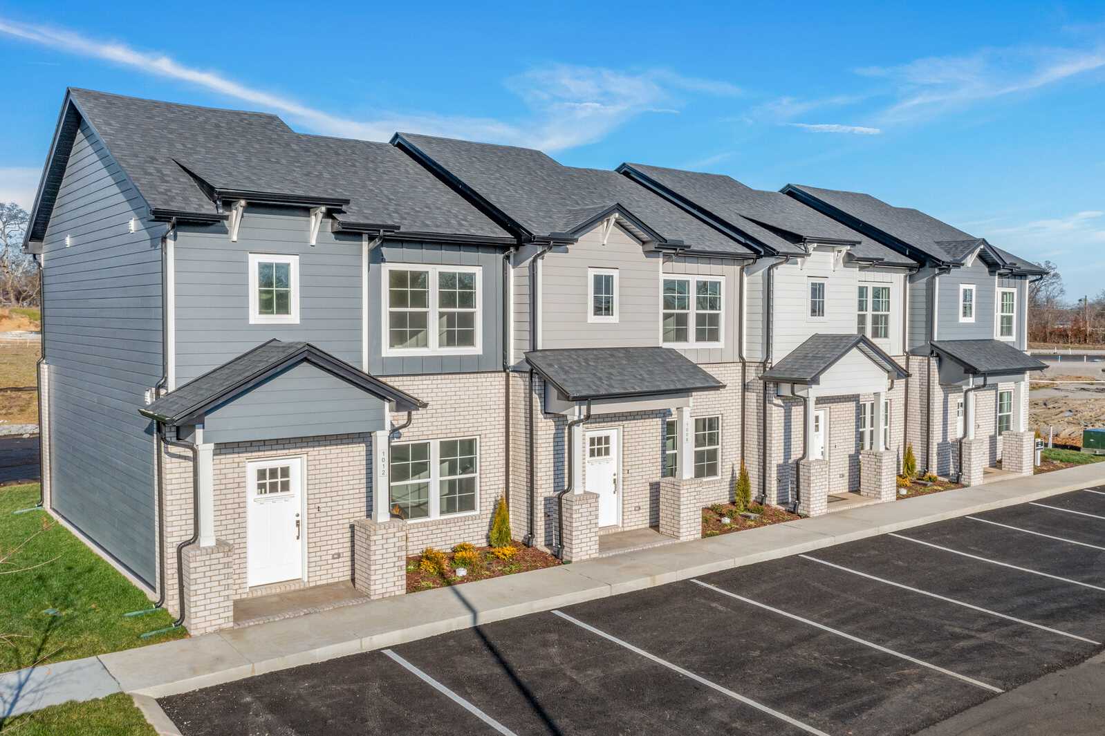Row of modern townhomes at The Towns at Red River in Gallatin TN with gray siding, white trim, and landscaped entries