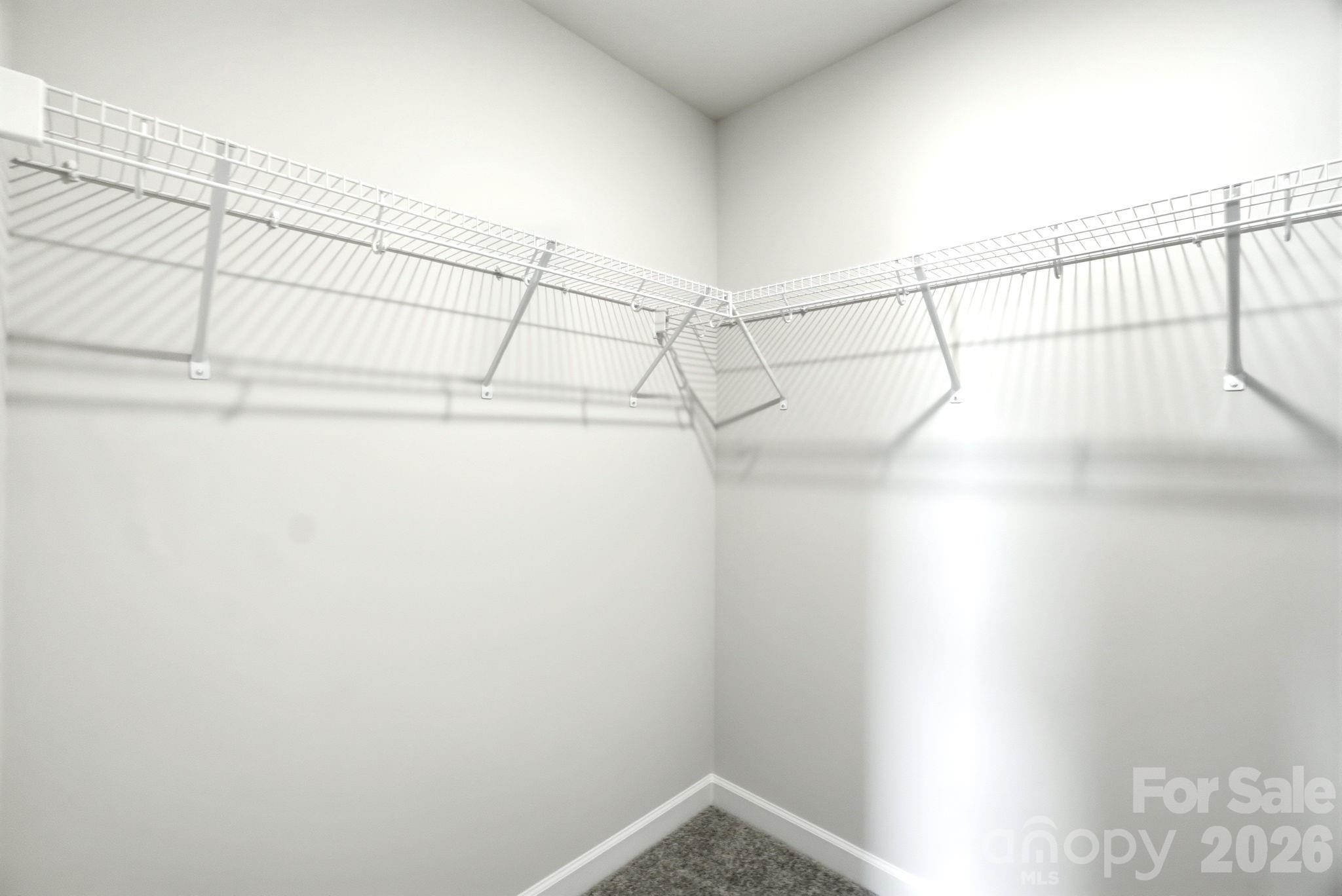 Walk-in closet with white wire shelving in The Magnolia B floor plan at Windgate in Mooresville, North Carolina.