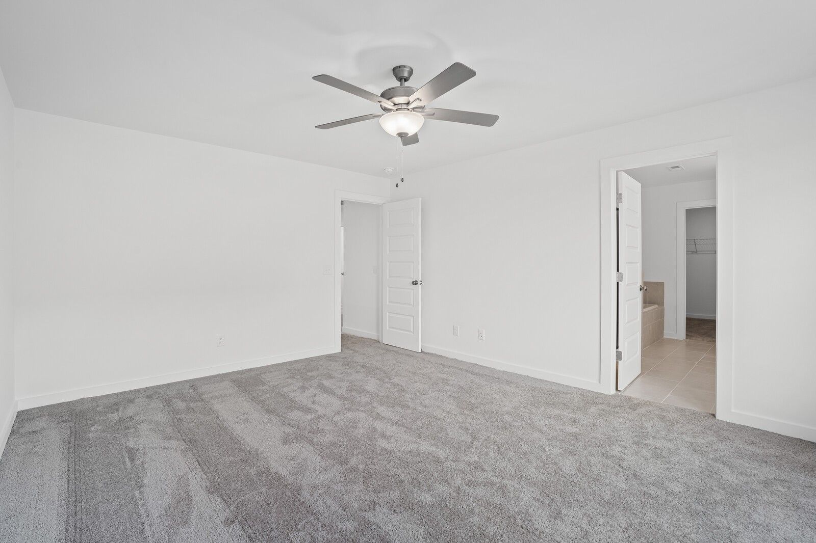 Spacious primary bedroom with grey carpet and ceiling fan in The Logan C floor plan at Calista Farms, White House, TN.