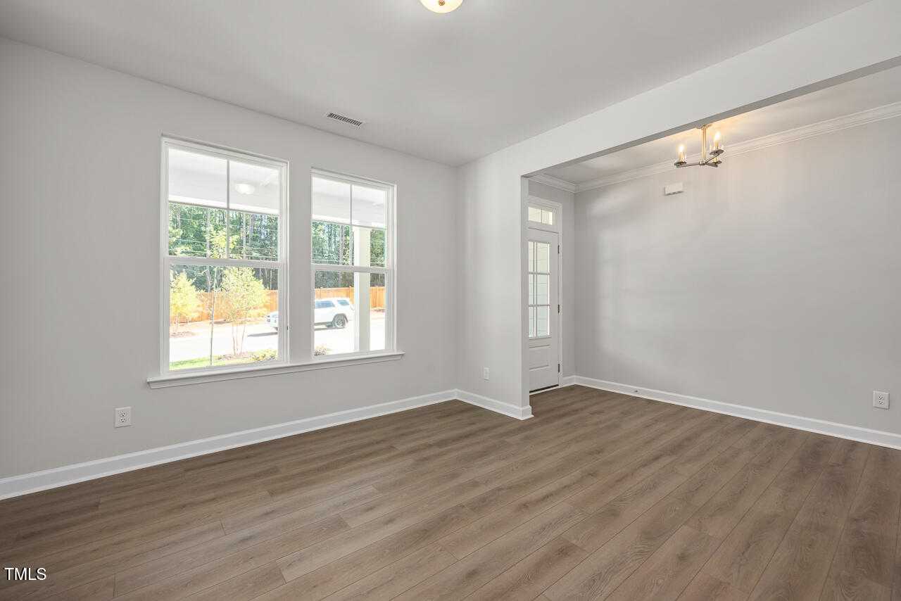 Bright foyer with large windows, chandelier, white door, and warm hardwood floors in Davidson Homes The Aspen C, Wake Forest, NC