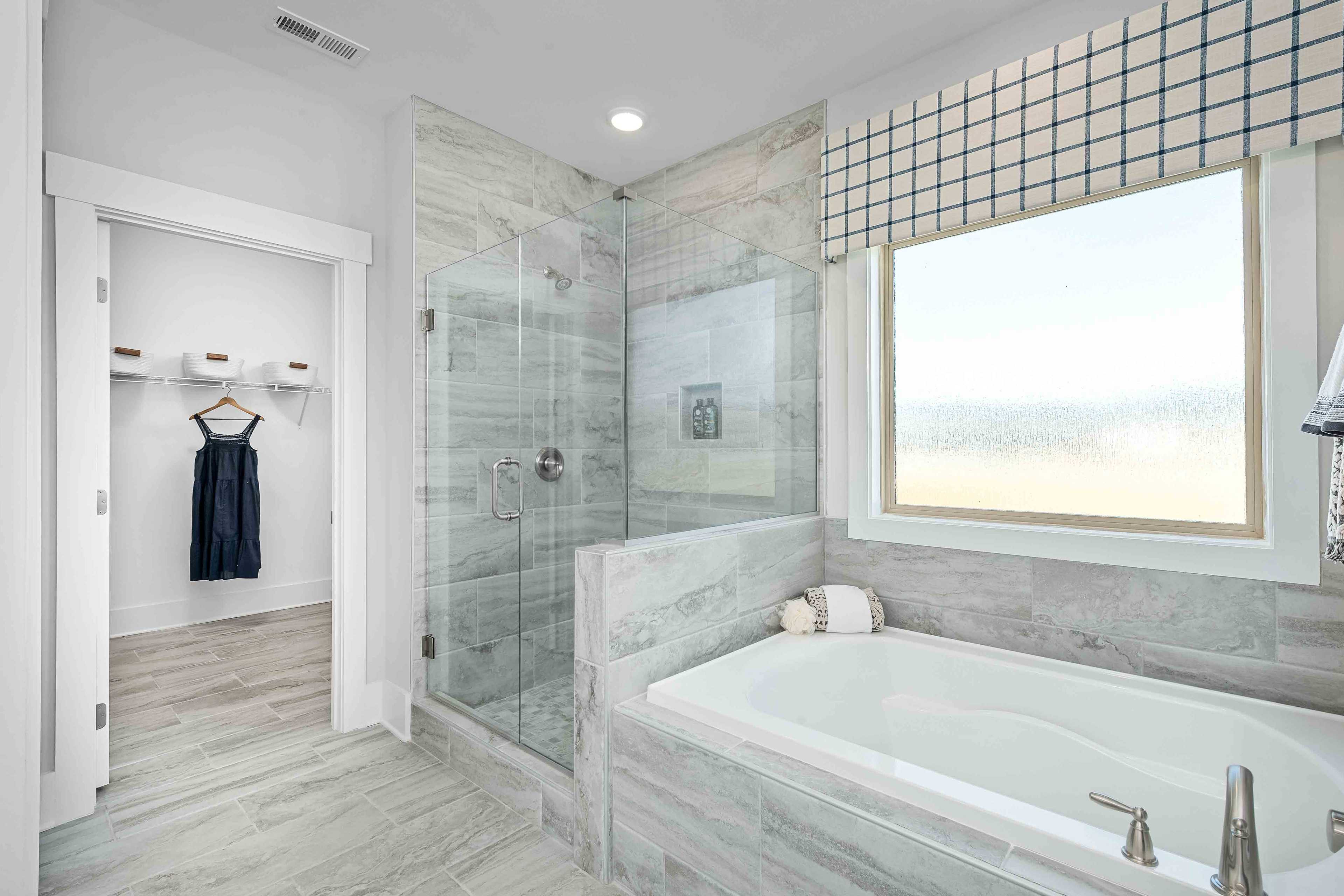 Luxurious master bathroom at Cain Park in Hartselle Alabama with freestanding tub glass shower gray tile and walk-in closet