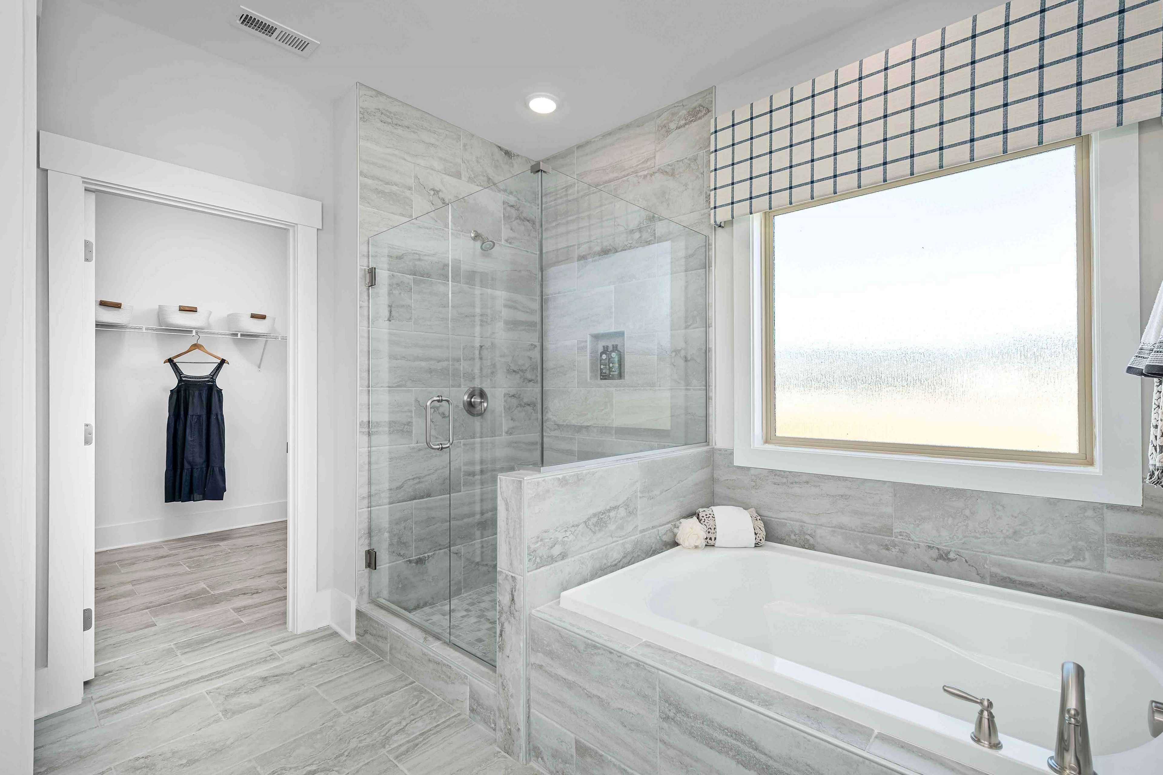 Luxurious master bathroom at Cain Park in Hartselle Alabama with freestanding tub glass shower gray tile and walk-in closet