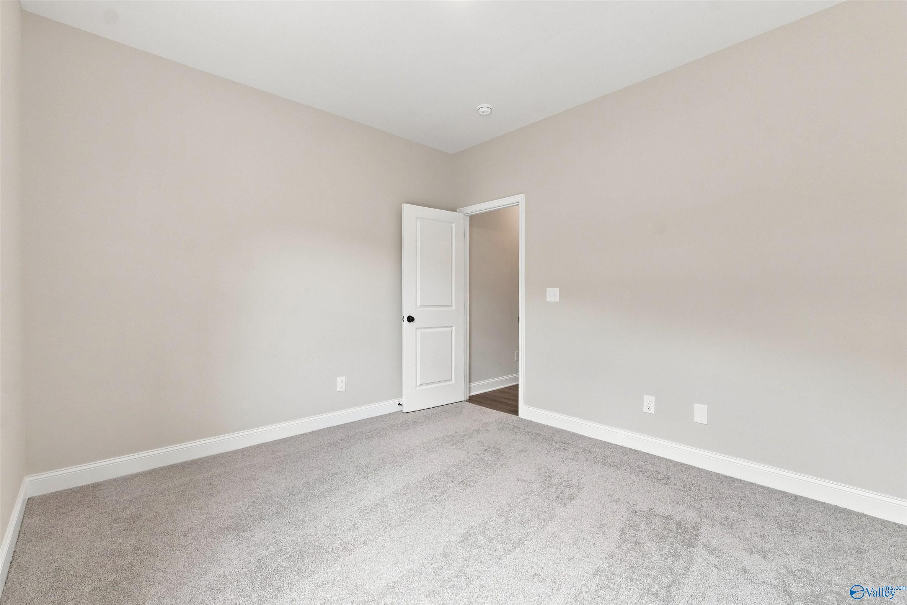 Bright carpeted bedroom with neutral walls and white trim in Davidson Homes' The Everett B floor plan, Wood Trail, Toney, Alabama