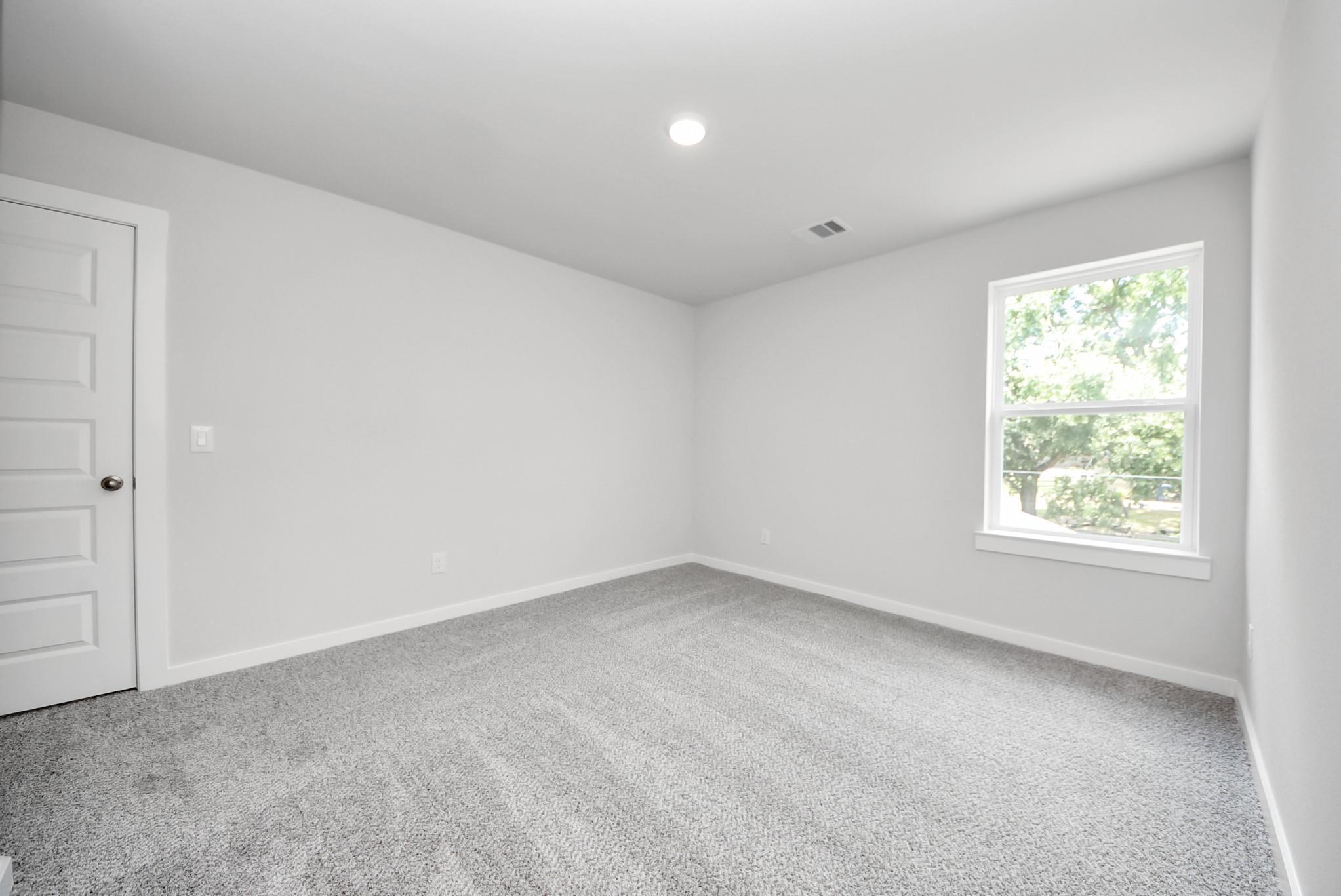 Spacious bedroom with plush carpet and natural light in The Sabine E floor plan by Davidson Homes in Magnolia, Texas.