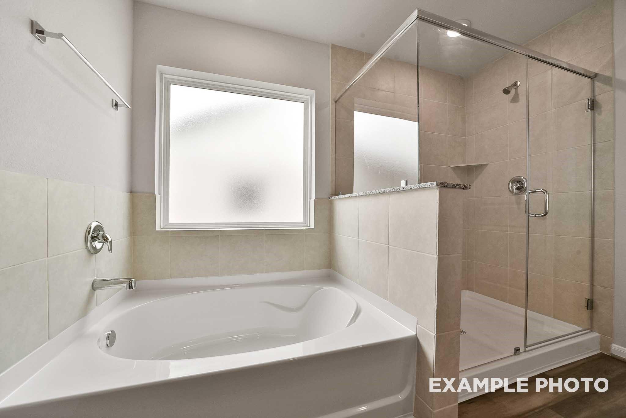 Spacious master bathroom with soaking tub, frameless glass shower, and frosted window in Davidson Homes The Tierra B, Beasley, Texas