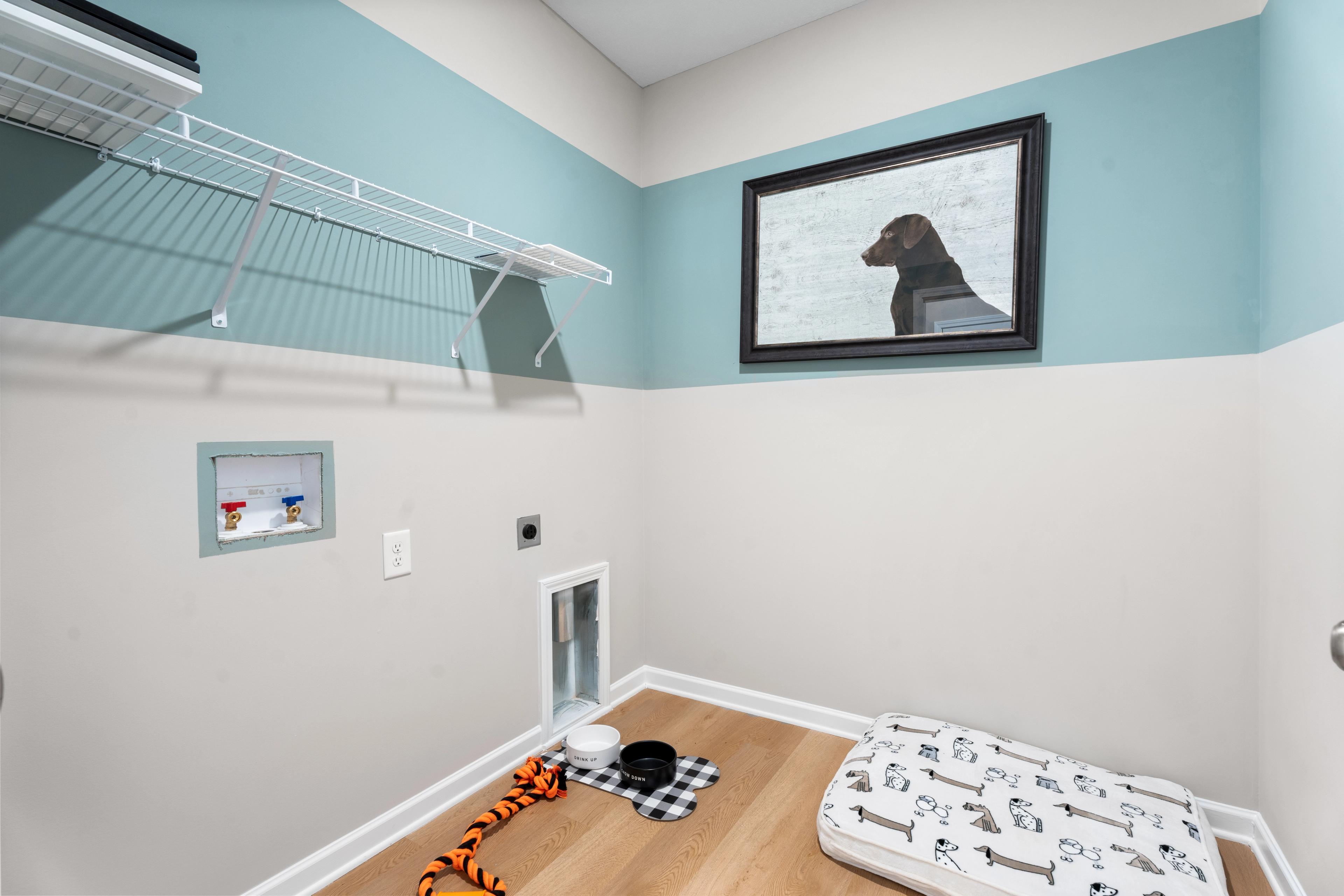 Cozy pet room with dog bed, bowls, pet door, and washer-dryer in Silver Oak, Cusseta Alabama by Evermore Homes
