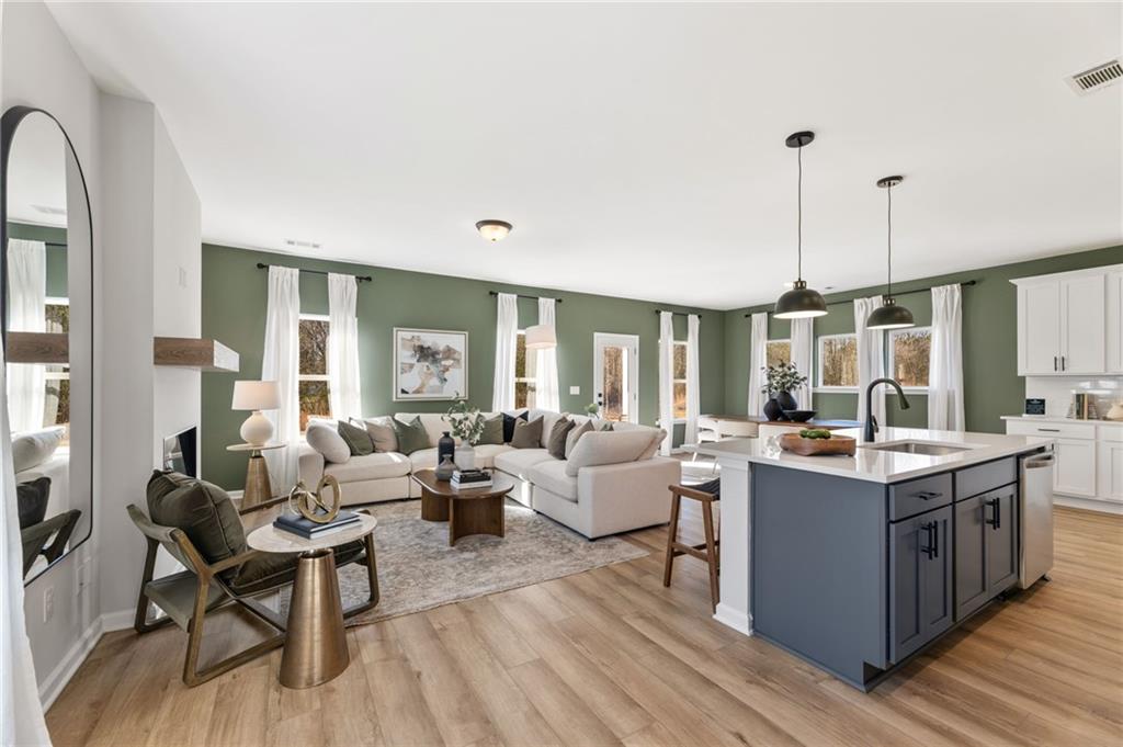 Open-concept living room and kitchen with sage green walls in The Rabun B floor plan at The Bluffs, Canton, Georgia.