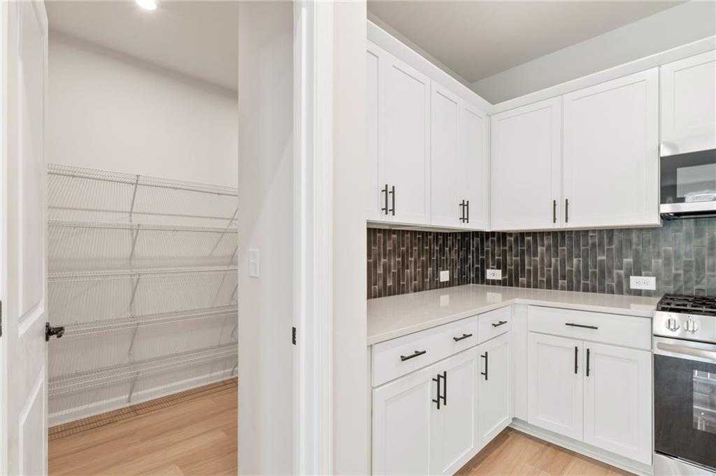 Modern white kitchen with stainless appliances, subway tile backsplash, and open pantry in Davidson Homes The Daphne C, Loganville