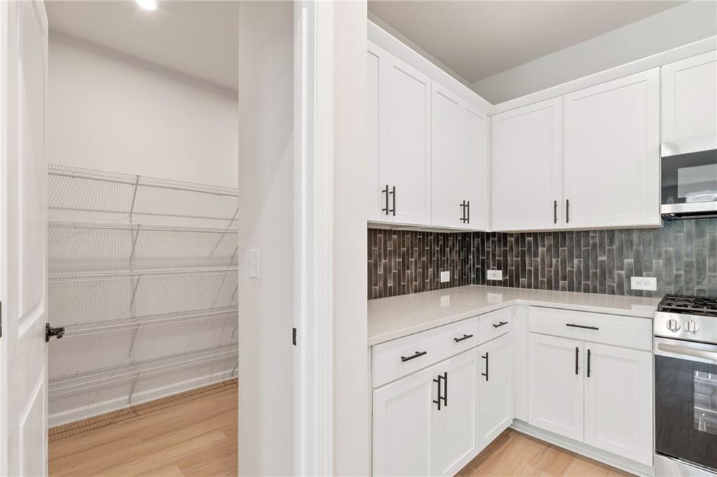 Modern white kitchen with subway tile backsplash, stainless appliances, and open pantry in Davidson Homes The Daphne C, Loganville, GA