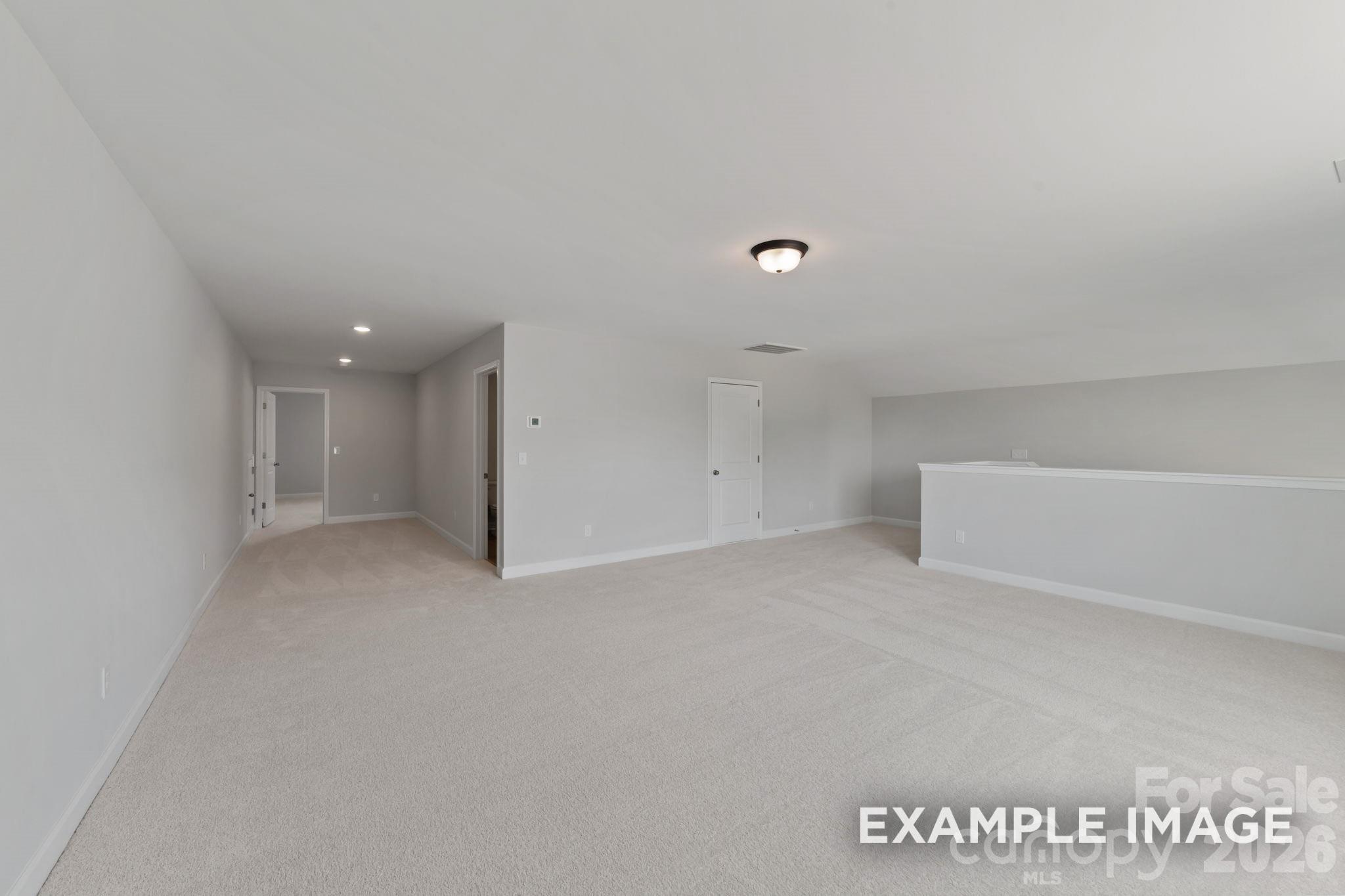 Spacious carpeted bonus room in The Magnolia B floor plan by Davidson Homes in Windgate, Mooresville, North Carolina.