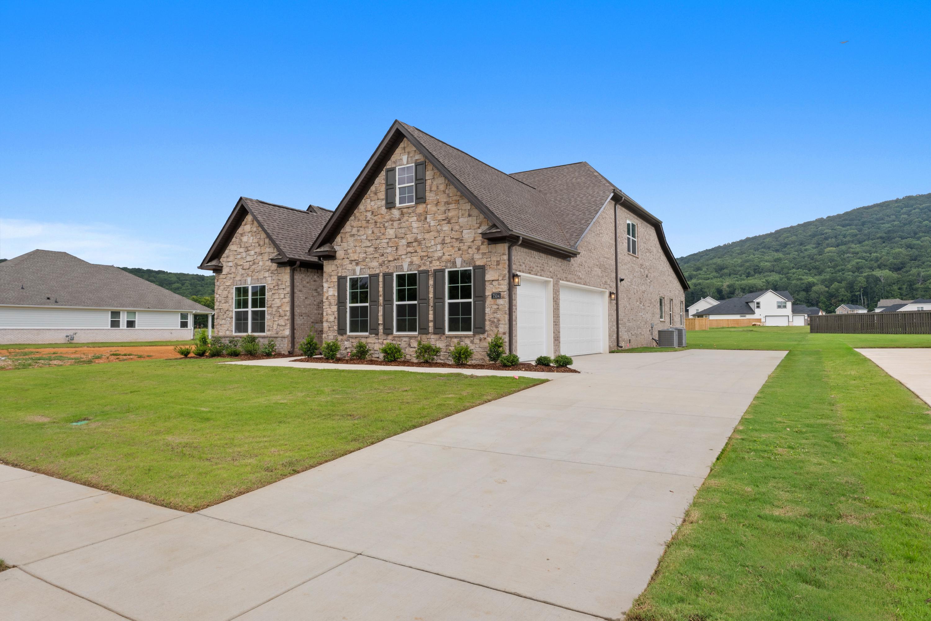 Two-story Oxford C home by Evermore Homes with stone siding exterior, gabled roof, 3-car garage, driveway, and green lawn in Owens Cross Roads