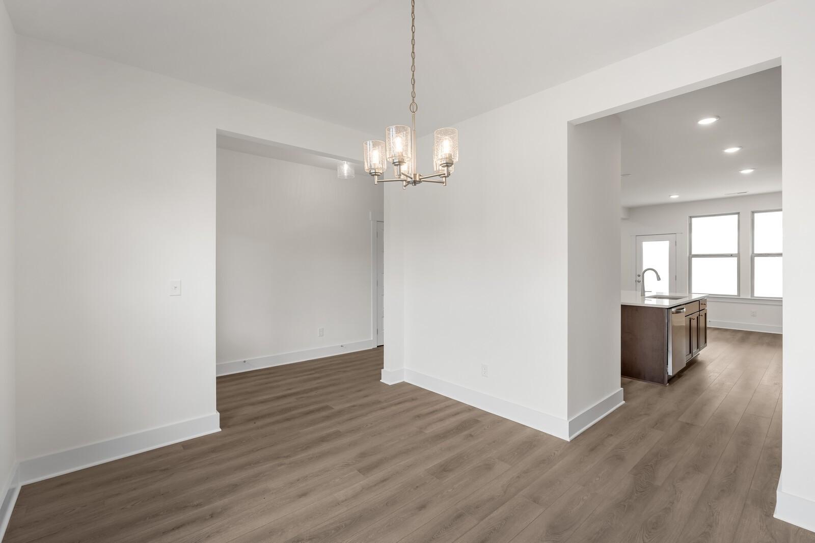 Elegant dining room with modern chandelier and open archway to kitchen in Davidson Homes The Willow C, Gallatin, TN