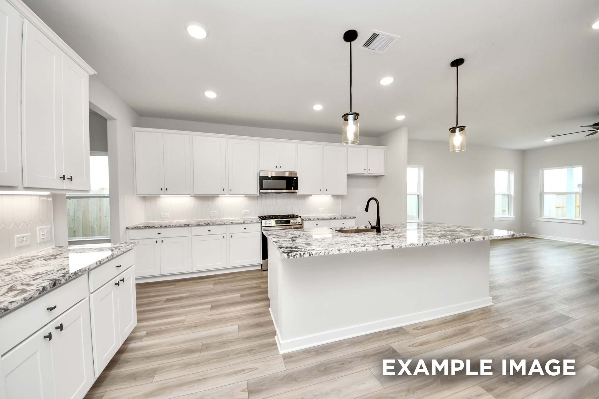 Modern kitchen in The Sorrento featuring white cabinetry, granite countertops, and a large island in an open-concept layout.