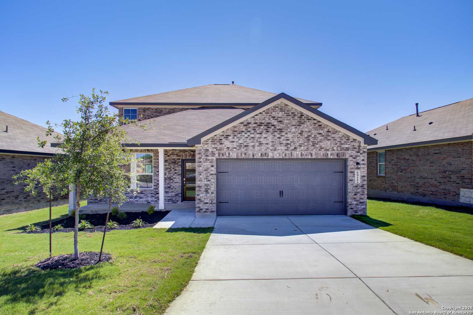 Modern two-story brick home with 2-car garage, front porch, and landscaped yard in Comanche Ridge, San Antonio, Texas - Davidson Homes The Douglas G