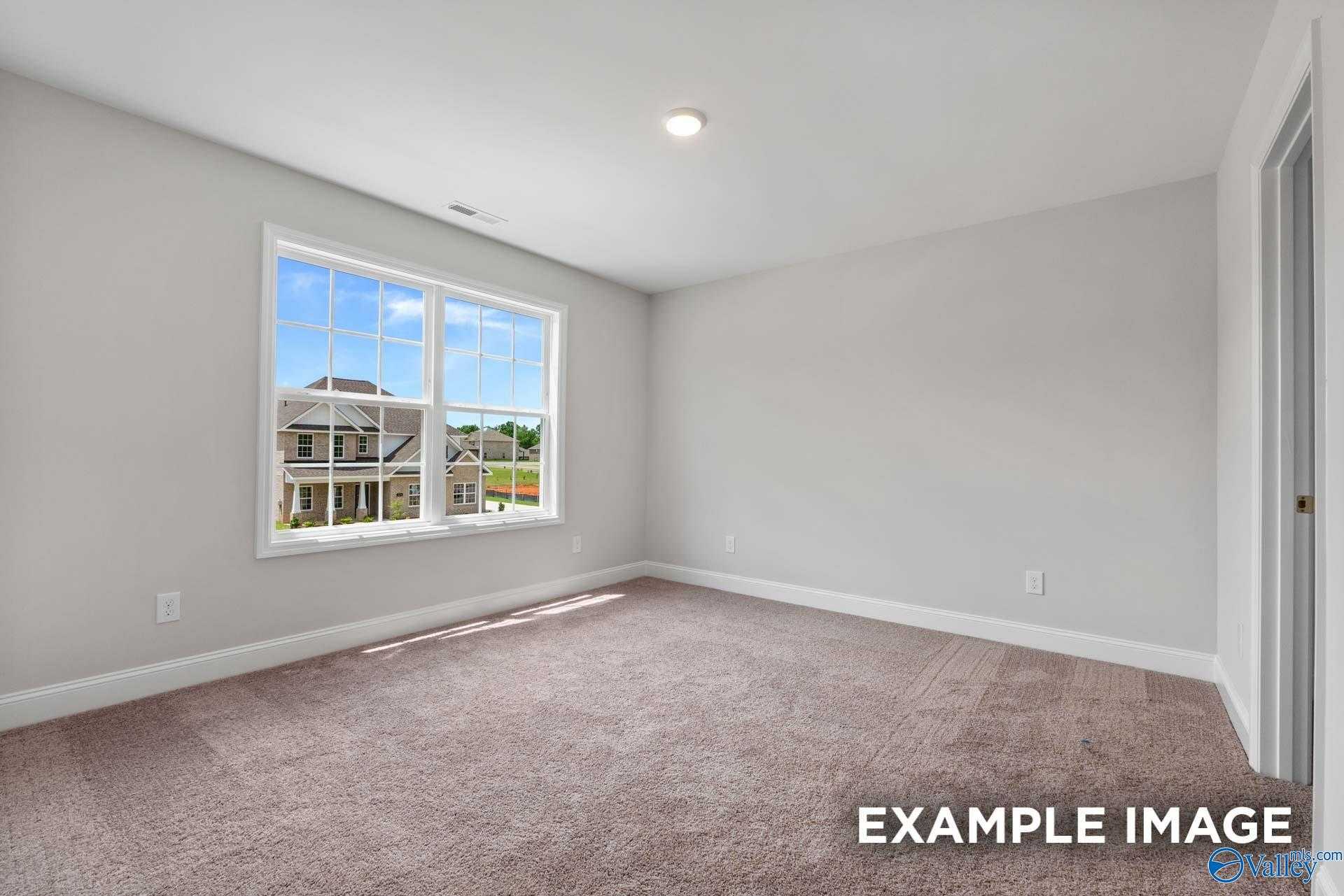 Bright empty bedroom with large window overlooking neighborhood, neutral walls, carpet in Shelby C floor plan, Meridianville, AL