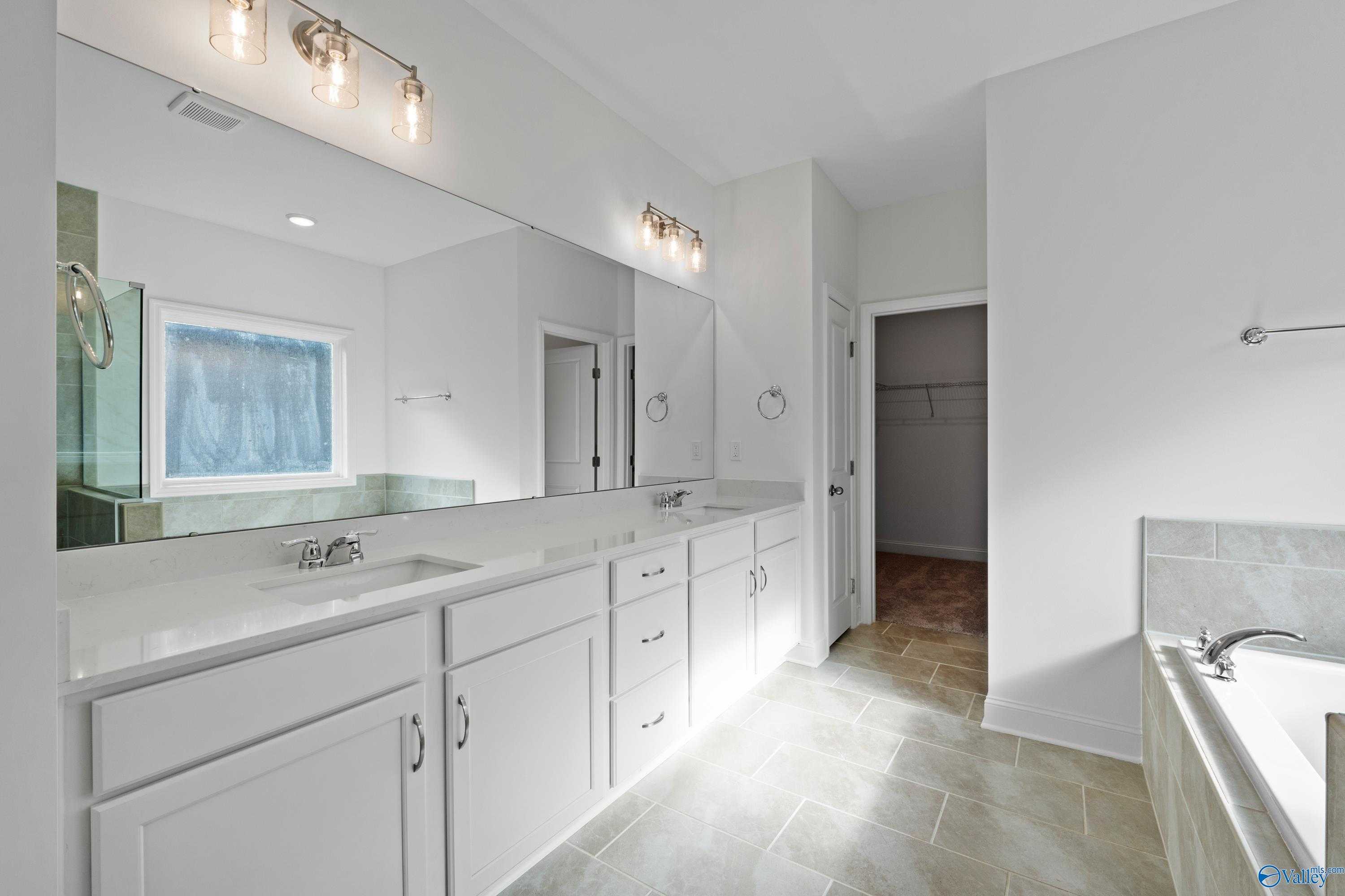 Elegant master bathroom with double vanity, freestanding tub, and large mirror in Davidson Homes The Oxford, Harvest, Alabama